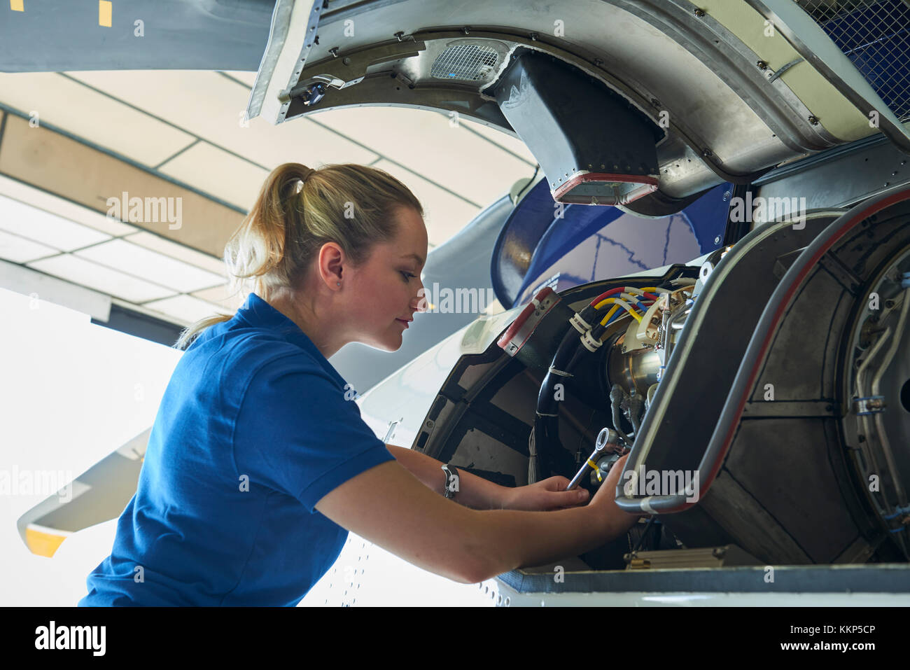 Weibliche aero Engineer, der an Helikopter im Hangar Stockfoto