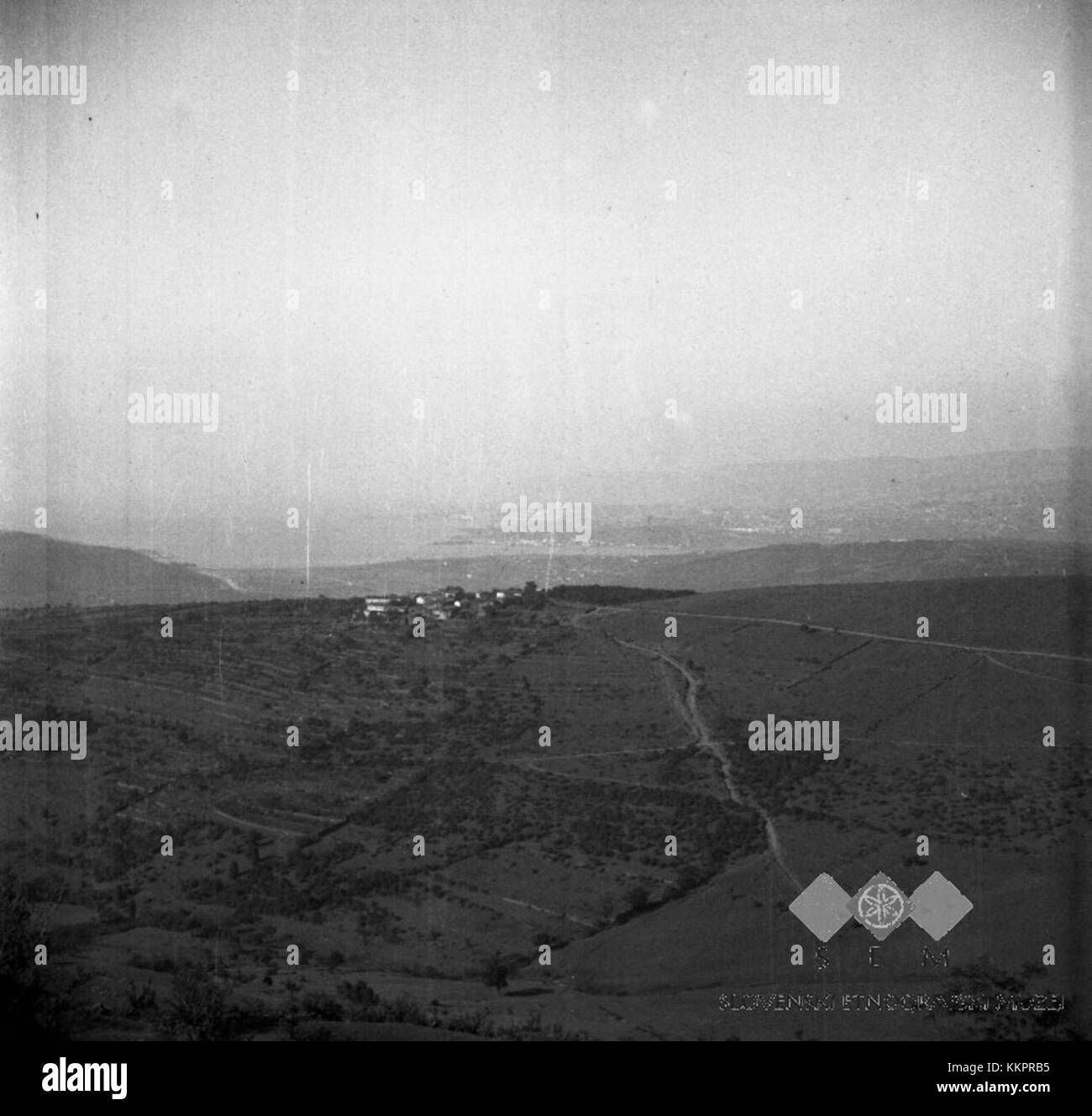 Dieses 1949 aufgenommene Foto zeigt einen Blick auf die Urbance von Tinjana aus mit der Stadt Triest im Hintergrund. Das Bild erfasst die historische Landschaft der Region und hebt die kulturellen und geografischen Besonderheiten der Region hervor. Stockfoto