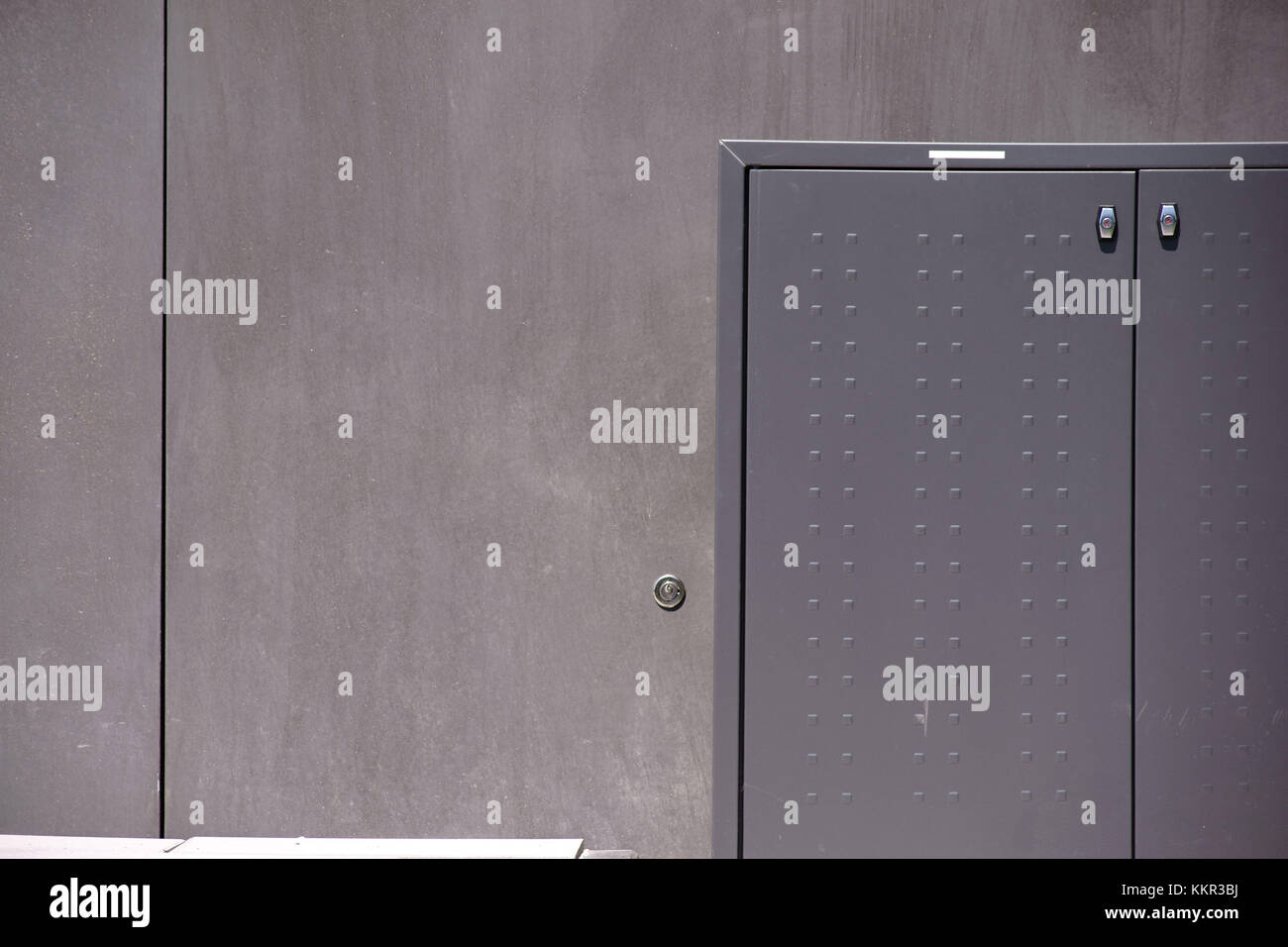 Die Fotografie von einem grauen elektrischen Anschlussdose vor einer glatten dunklen graue Wand. Stockfoto