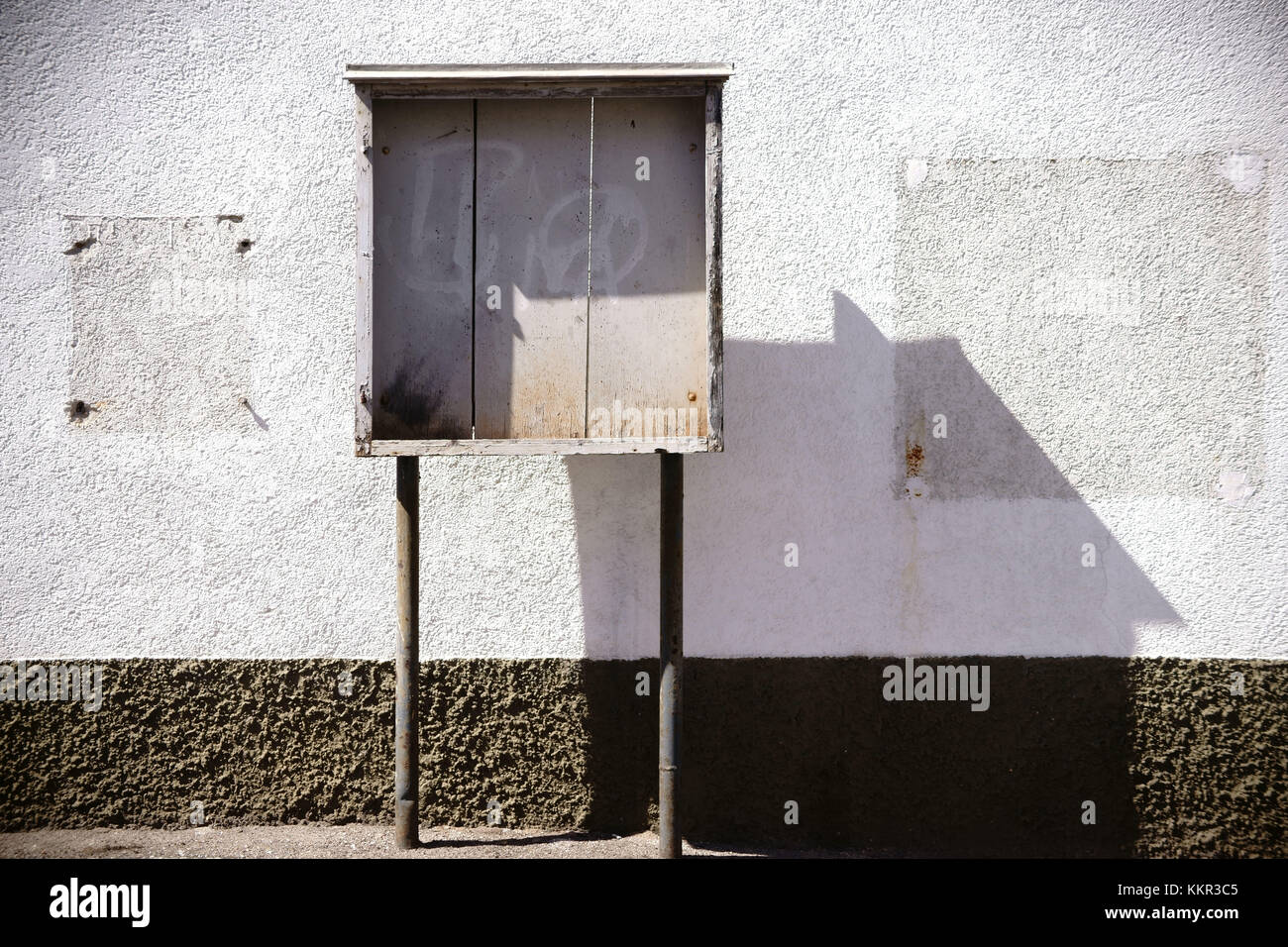 Eine alte Holzvitrine, die an einer Fassade eines Gebäudes mit fehlendem Zigarettenautomat und Holzrahmen steht. Stockfoto