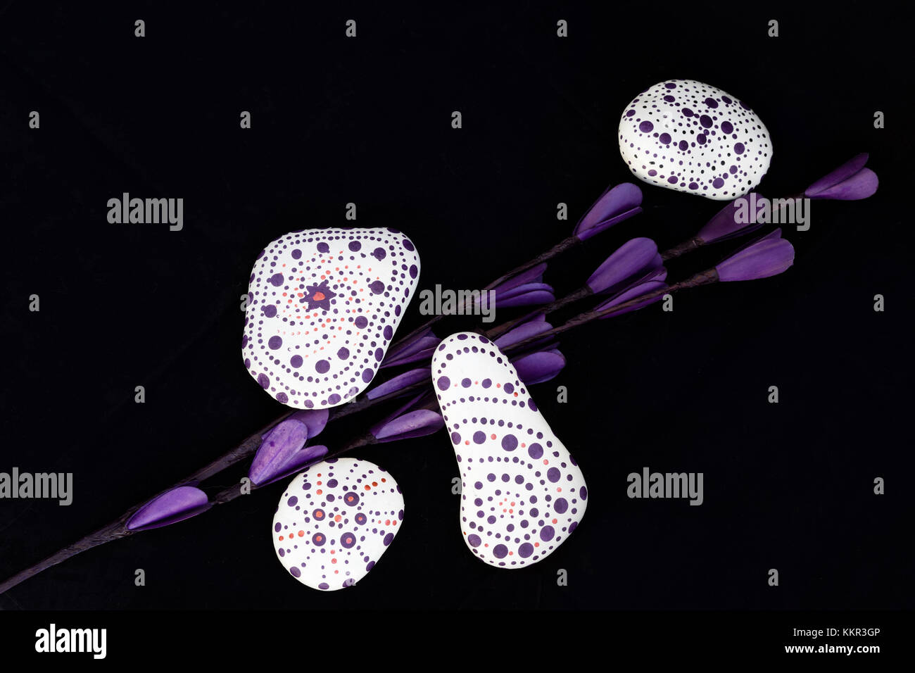 Bemalte Steine und lila Blüten, Stein Kunst Stockfoto