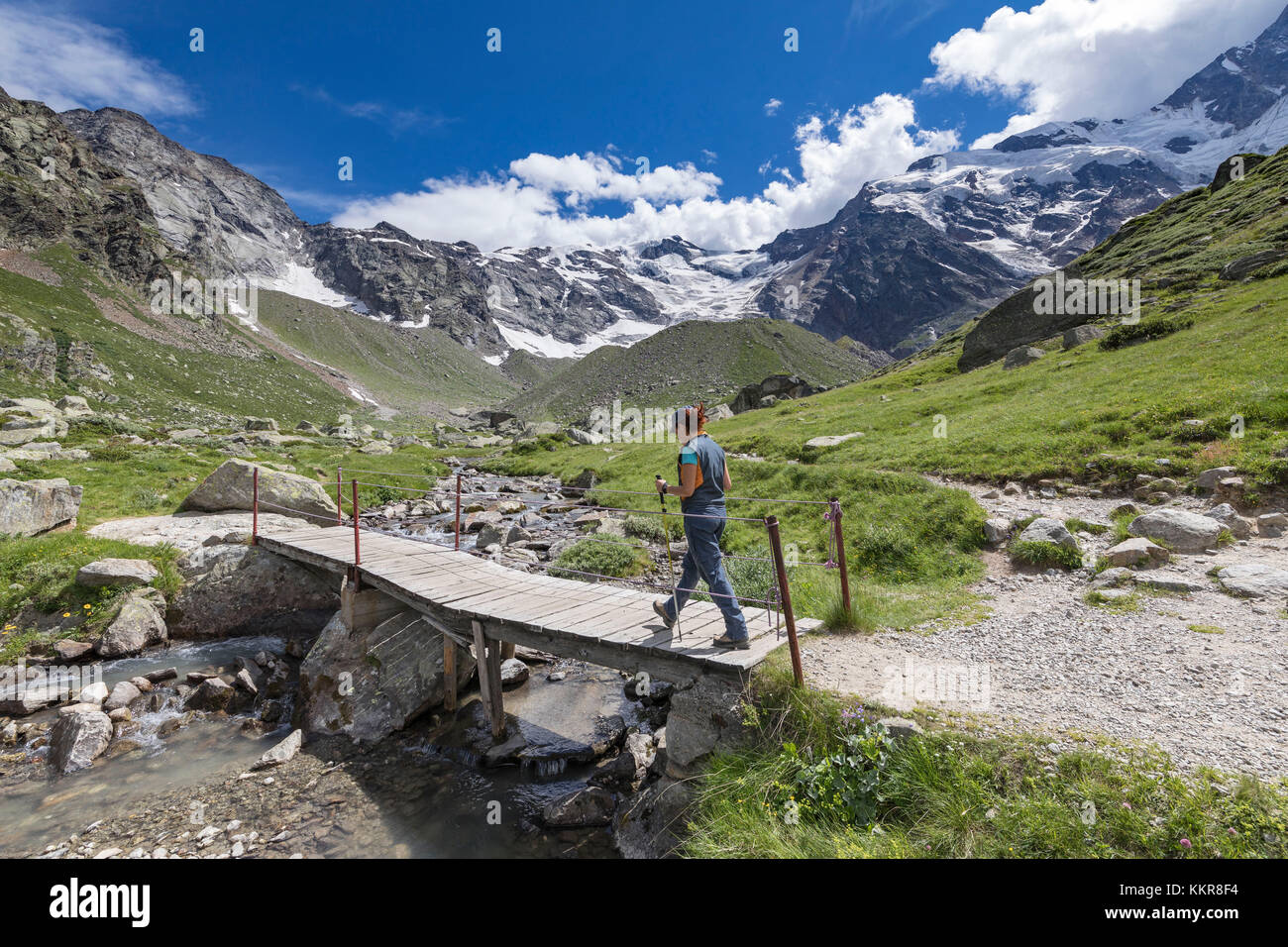 Ein trekker kreuzt eine kleine Holzbrücke in der Nähe der Zamboni Zappa Zuflucht am Fuße der Ostwand des Monte Rosa Massivs (Macugnaga, Anzasca Valley, Provinz Verbano Cusio Ossola, Piemont, Italien, Europa) Stockfoto