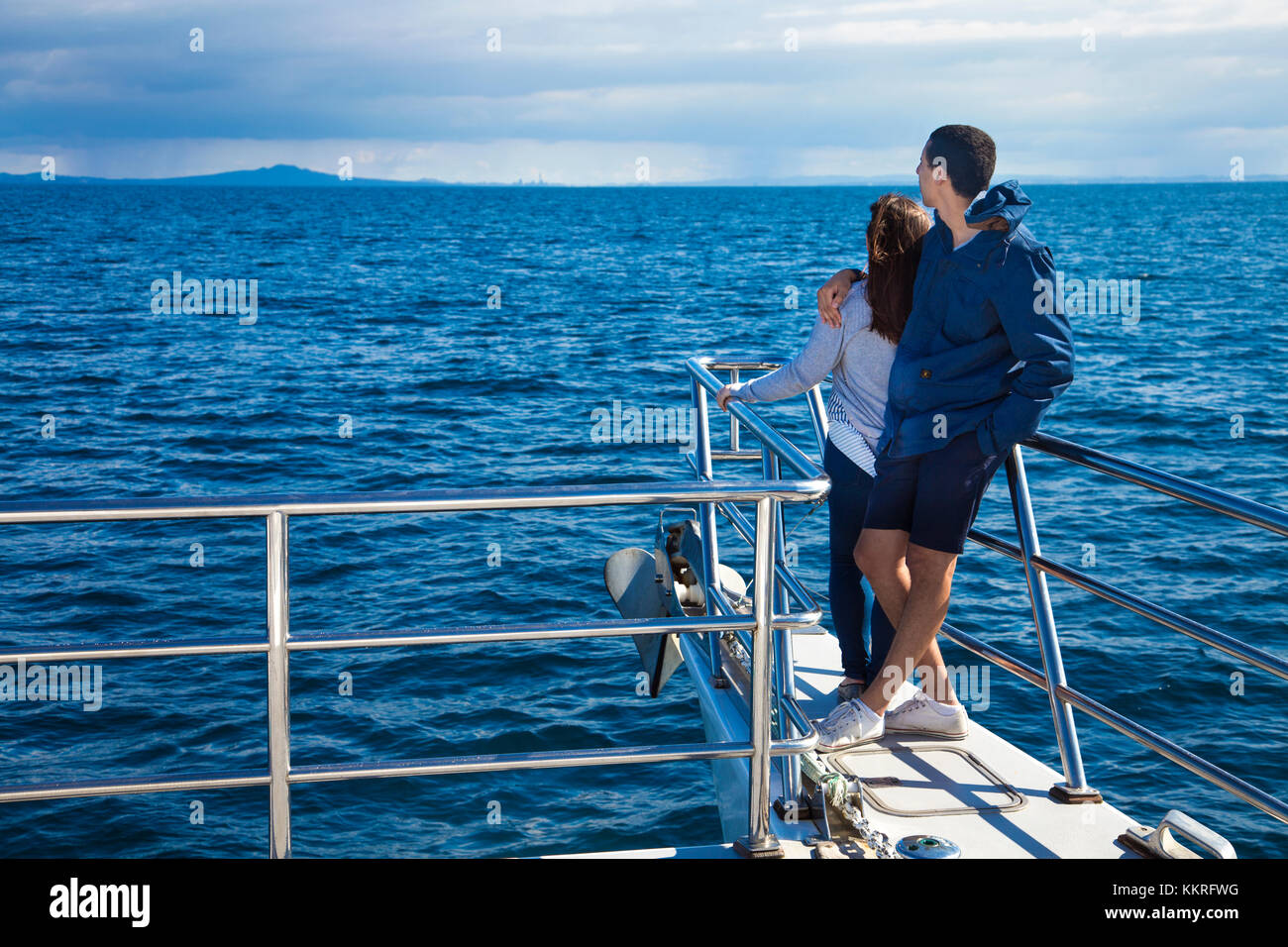 Ein paar einander umarmen, mit Blick aufs Meer auf einem Kreuzfahrtschiff (Wal und Delphin Safari, Auckland, Neuseeland) Stockfoto