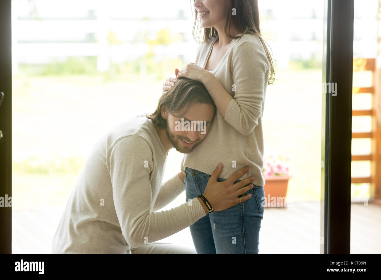 Glückliche Menschen, Ohr zu schwangere Frau Bauch zu Hause Stockfoto