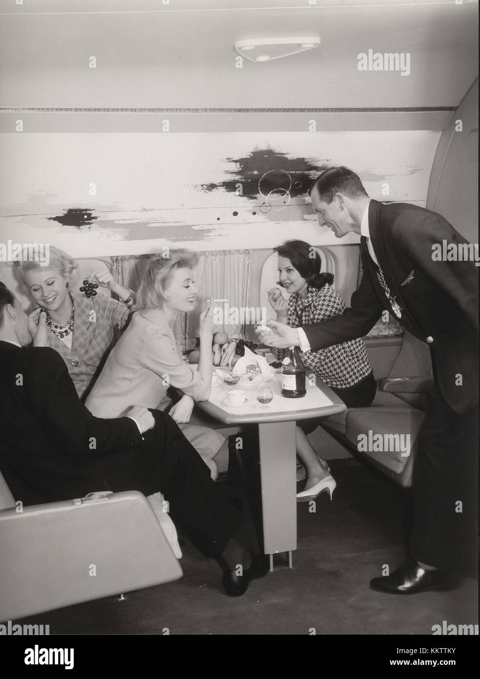 Dieses Bild aus den frühen 1960er Jahren fängt eine Szene an Bord eines DC 8-Flugzeugs ein und zeigt ein typisches Flugerlebnis der damaligen Zeit. Sie verdeutlicht die Unterschiede in Bezug auf Flugkomfort und -Technologie im Vergleich zu modernen Flügen. Stockfoto