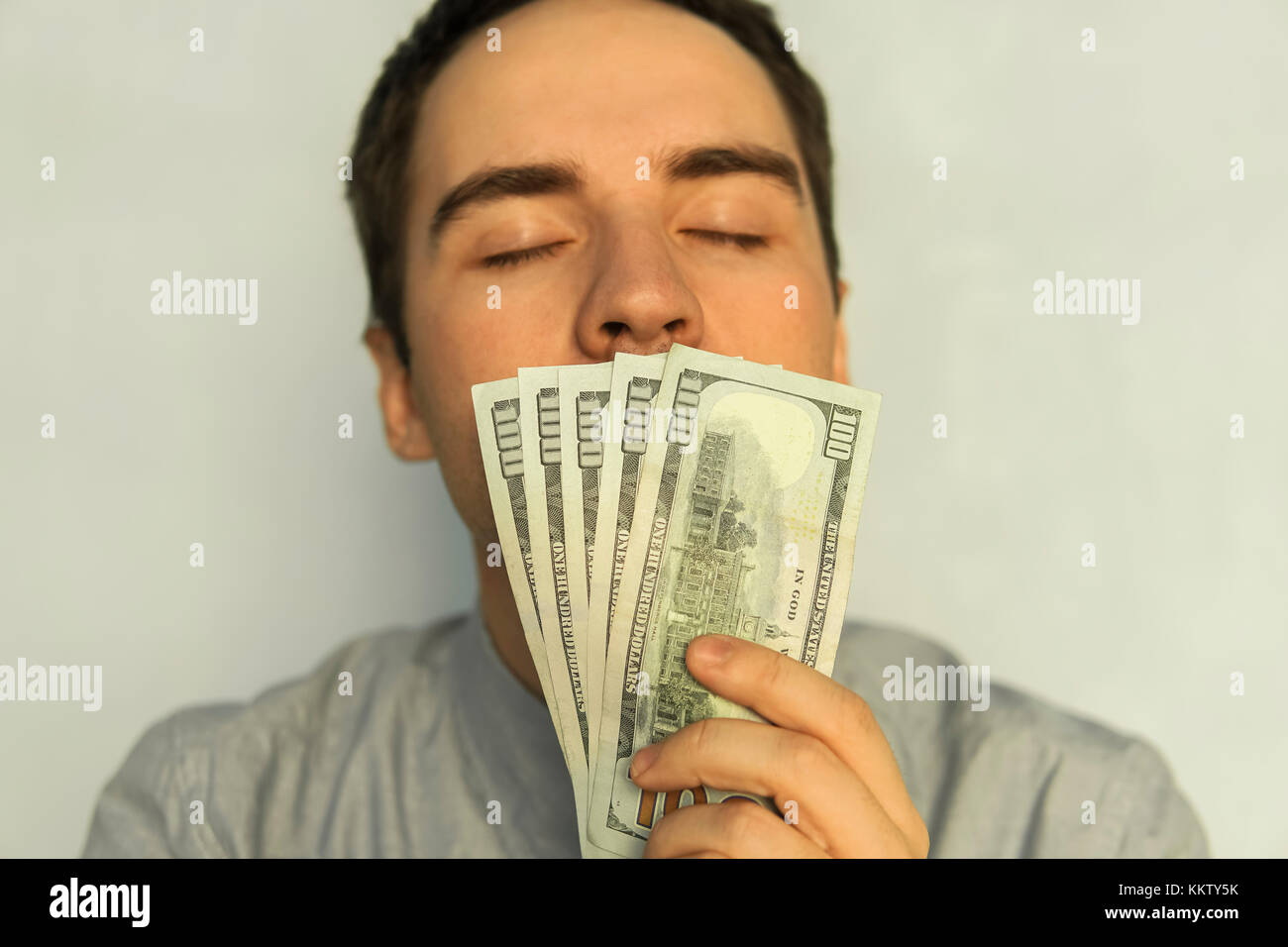 Business, Menschen und Finanzen Konzept - Geschäftsmann riechen amerikanischer Dollar Geld. Der süsse Geruch des Geldes. jungen Kerl sniffing 500 Dollar verdient Mon Stockfoto