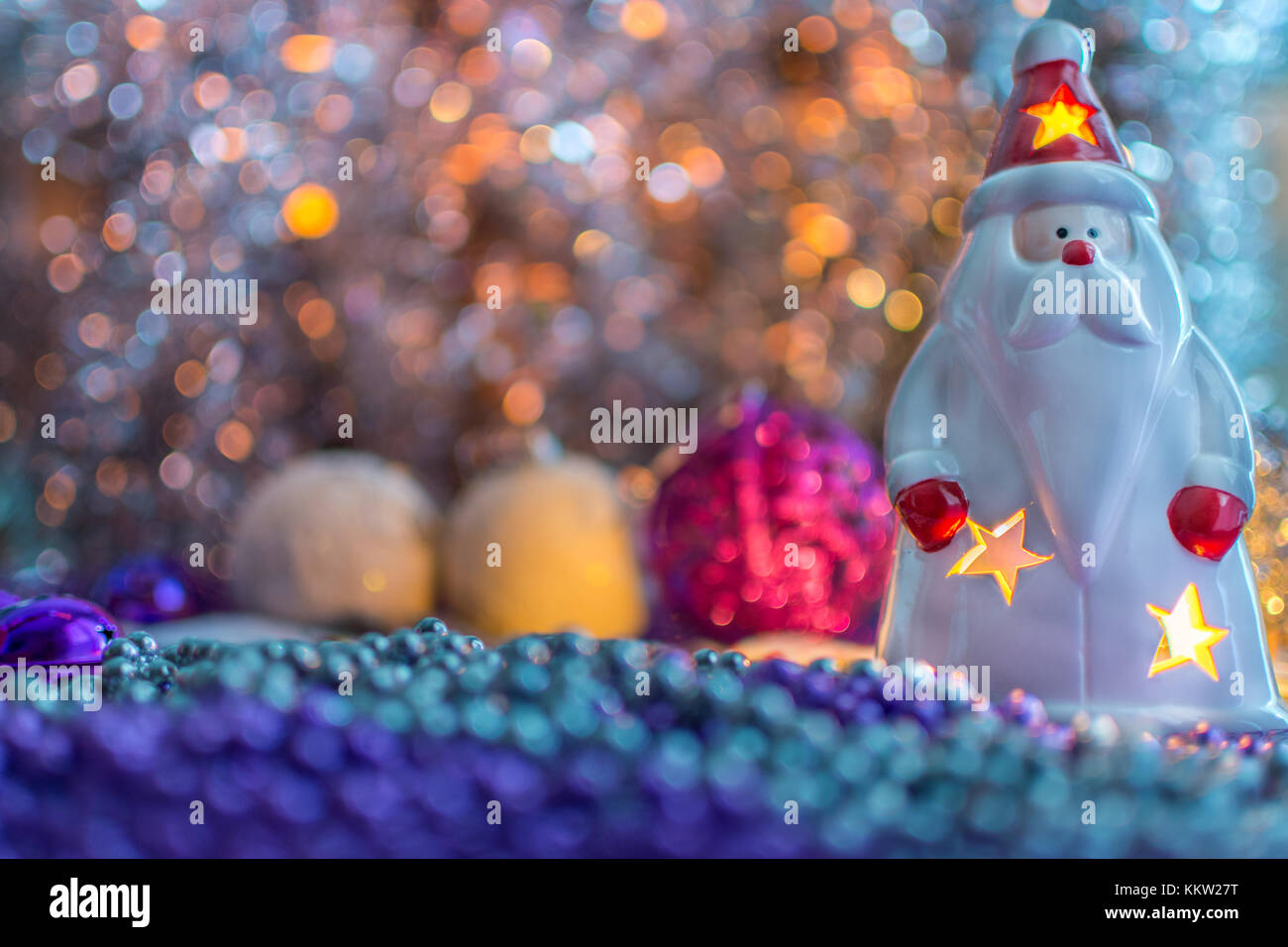 Bunte Weihnachtsdekorationen Santa mit einer Kerze im Innern, auf extrem geringe Tiefenschärfe und cremig gelben Hintergrund. Stockfoto