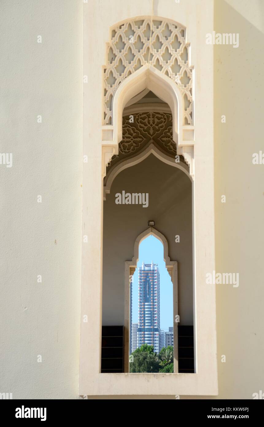 Der Kontrast zwischen Tradition und Moderne Islamische Architektur, mit einem hohen Turm durch die gewölbten Fenster einer Moschee. Stockfoto