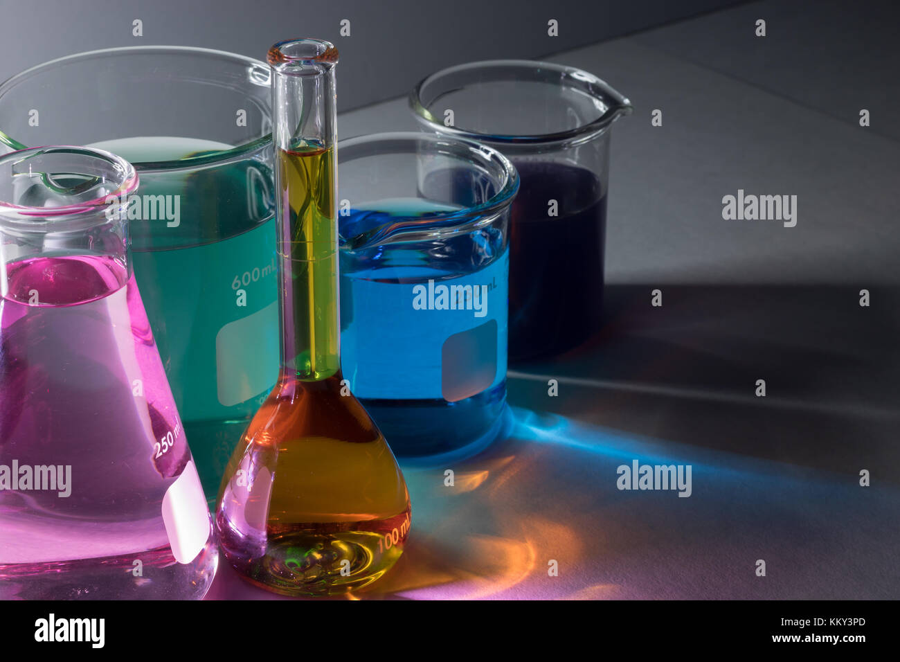 Hohe Betrachtungswinkel von Laborglas mit flüssigen Chemikalien über grauer Hintergrund Stockfoto