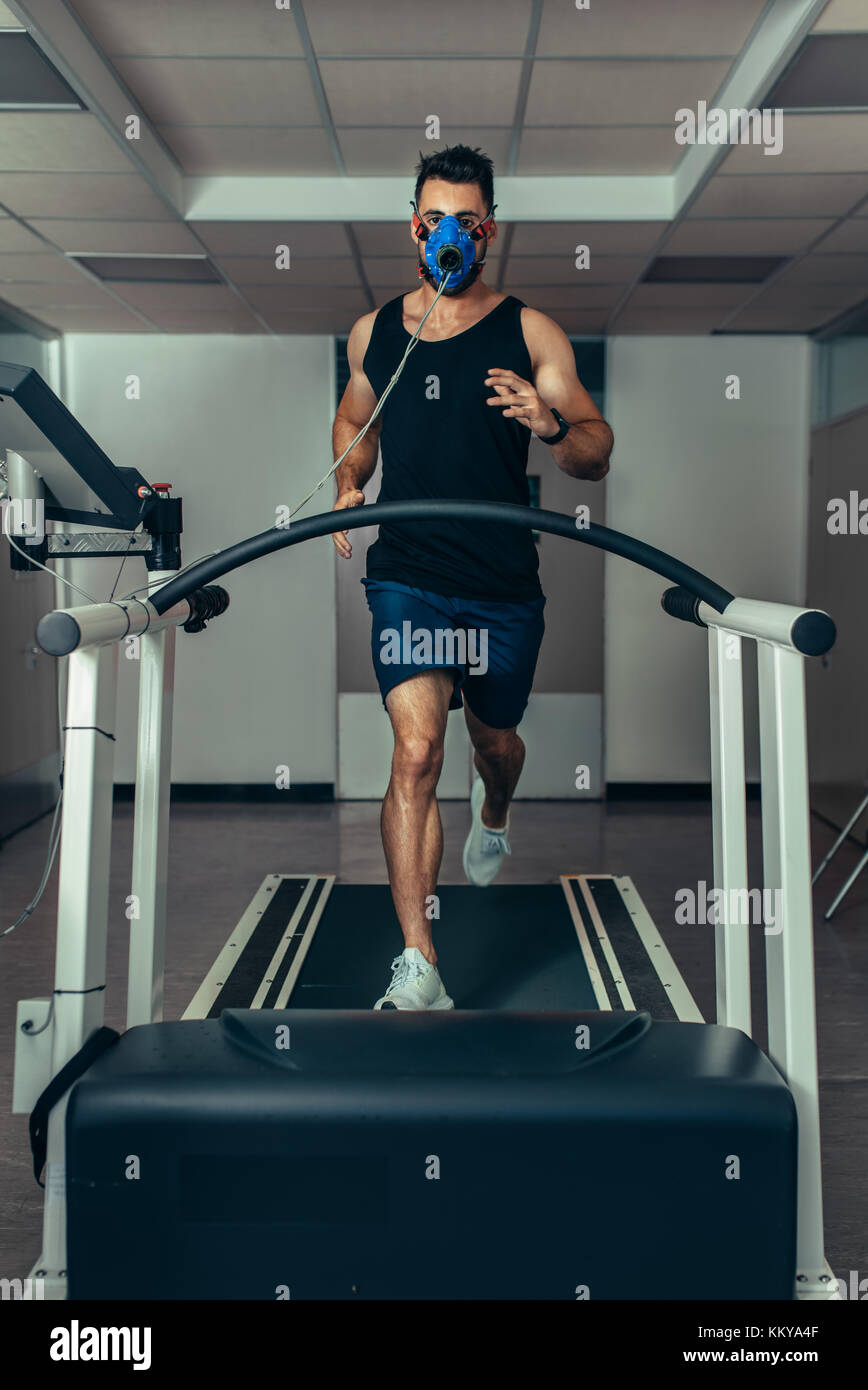 Männliche Läufer tragen Maske auf Laufband in Sport Science Laboratory.  Sport Mann laufen auf Laufband und seine Fitness Performance Monitoring  Stockfotografie - Alamy