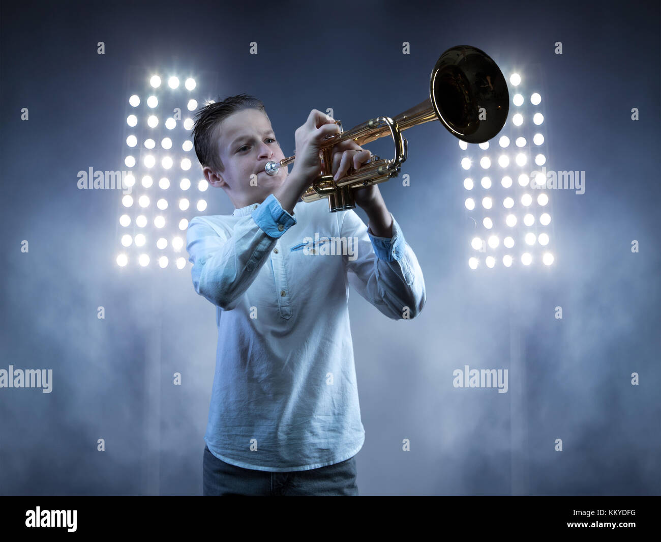Junge spielt Trompete mit blauen Nebel Stimmung und Bühne Licht im Hintergrund Stockfoto