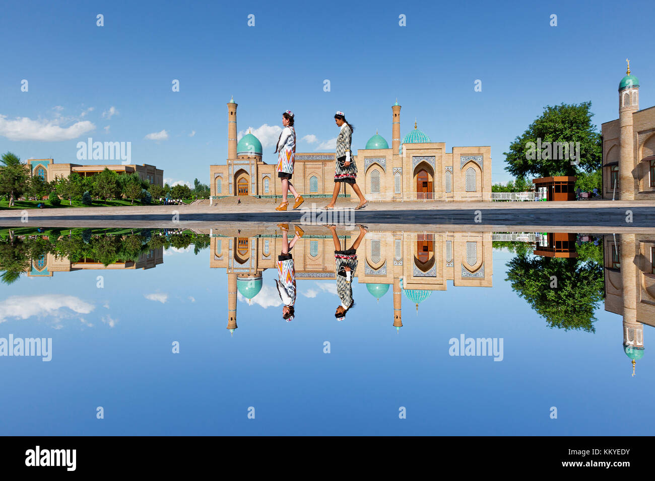Reflexion in der Pfütze von Wasser der Khast Imam Moschee wie Mädchen in seinem Innenhof gehen, in Taschkent, Usbekistan. Stockfoto