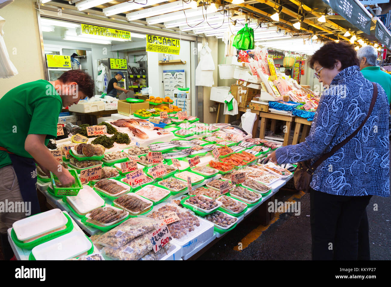 Tsukiji, Tokio, Japan - 17. Januar 2023 : ein japanischer Fischhändler bereitet frische Meeresfrüchte zum Verkauf zu und der Kunde kauft Fisch am Fischstand Stockfoto