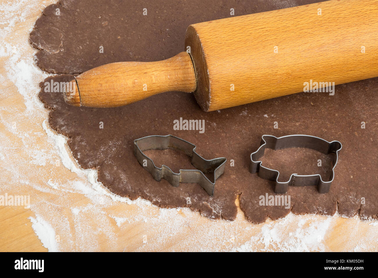 Flach ausgewalzter Teig, Rollstift und Plätzchenschneider. Nahaufnahme des Ausschneidens von Weihnachts-Lebkuchen auf der Konditorplatte. Stockfoto