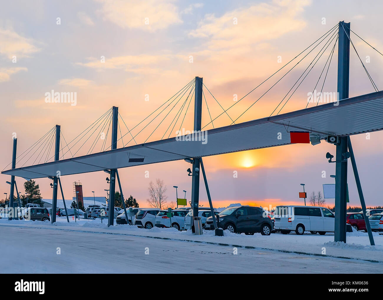 Autos parken am Flughafen Rovaniemi im Winter bei Sonnenuntergang Stockfoto