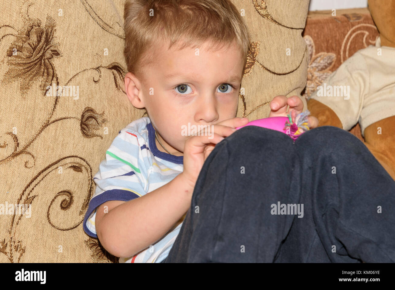 Portrait von blonden Jungen spielen mit Plastilin und zu Hause auf dem Sofa tragen Stockfoto