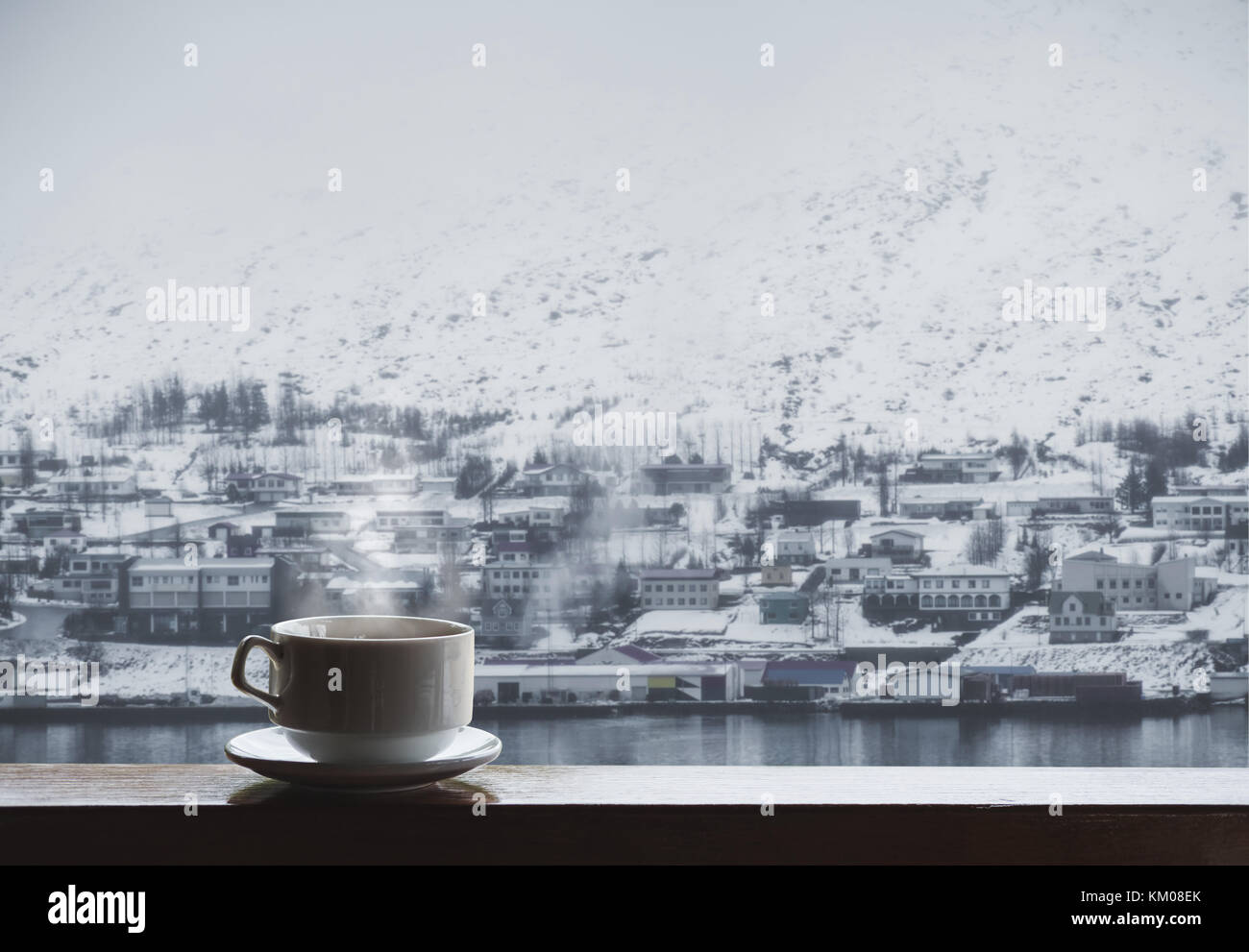 Tasse heißes Getränk mit Dampf auf Holz Tisch, Winter Dorf im Winter anzeigen Stockfoto
