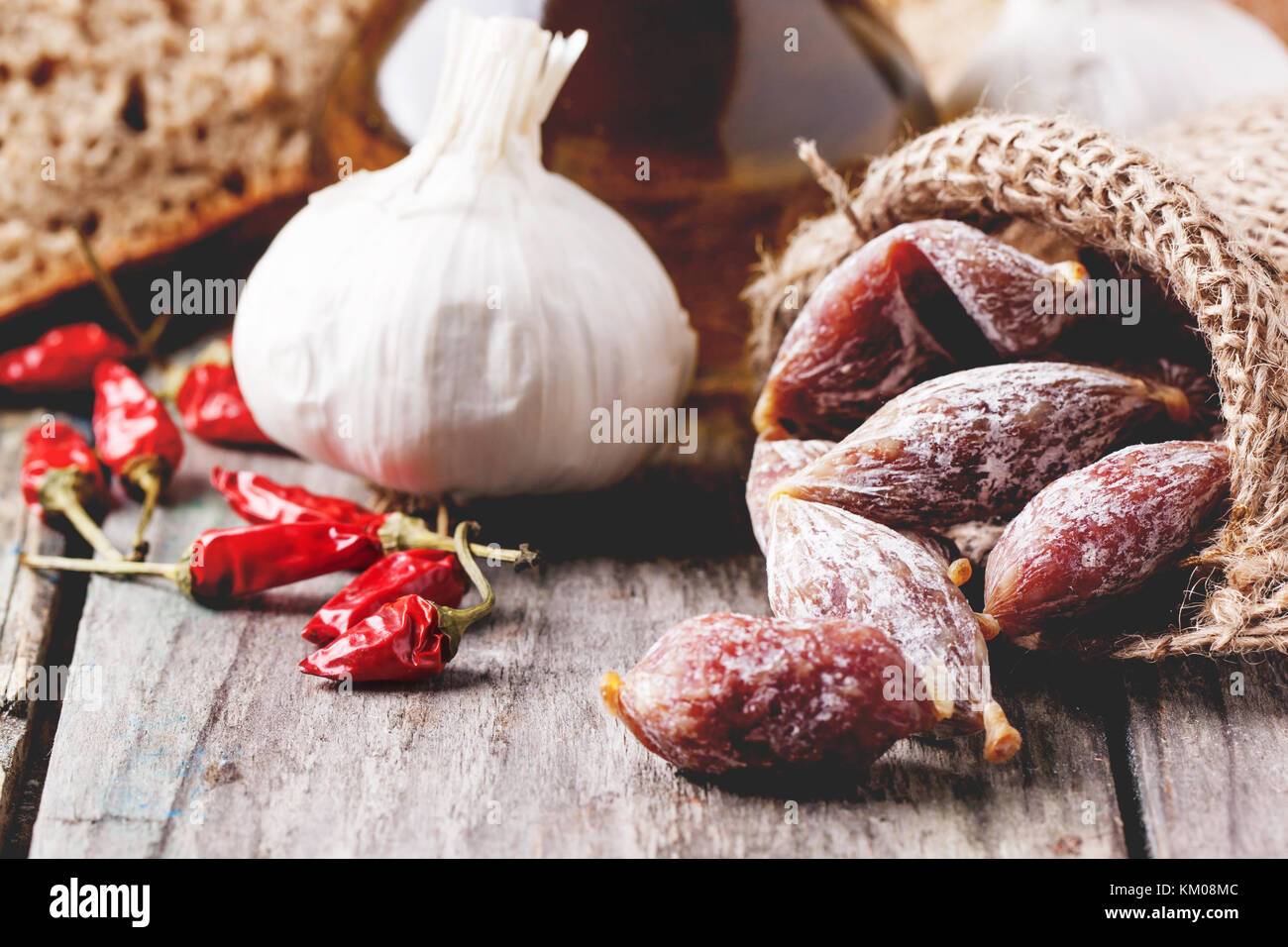 Wenig Salami in einem Sack mit Red Hot Chili Peppers und Knoblauch über alten Holztisch. siehe Serie. Stockfoto