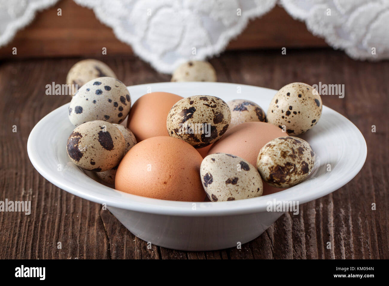 Wachtel und huhn eier in weiße Platte auf alten Holztisch Stockfoto
