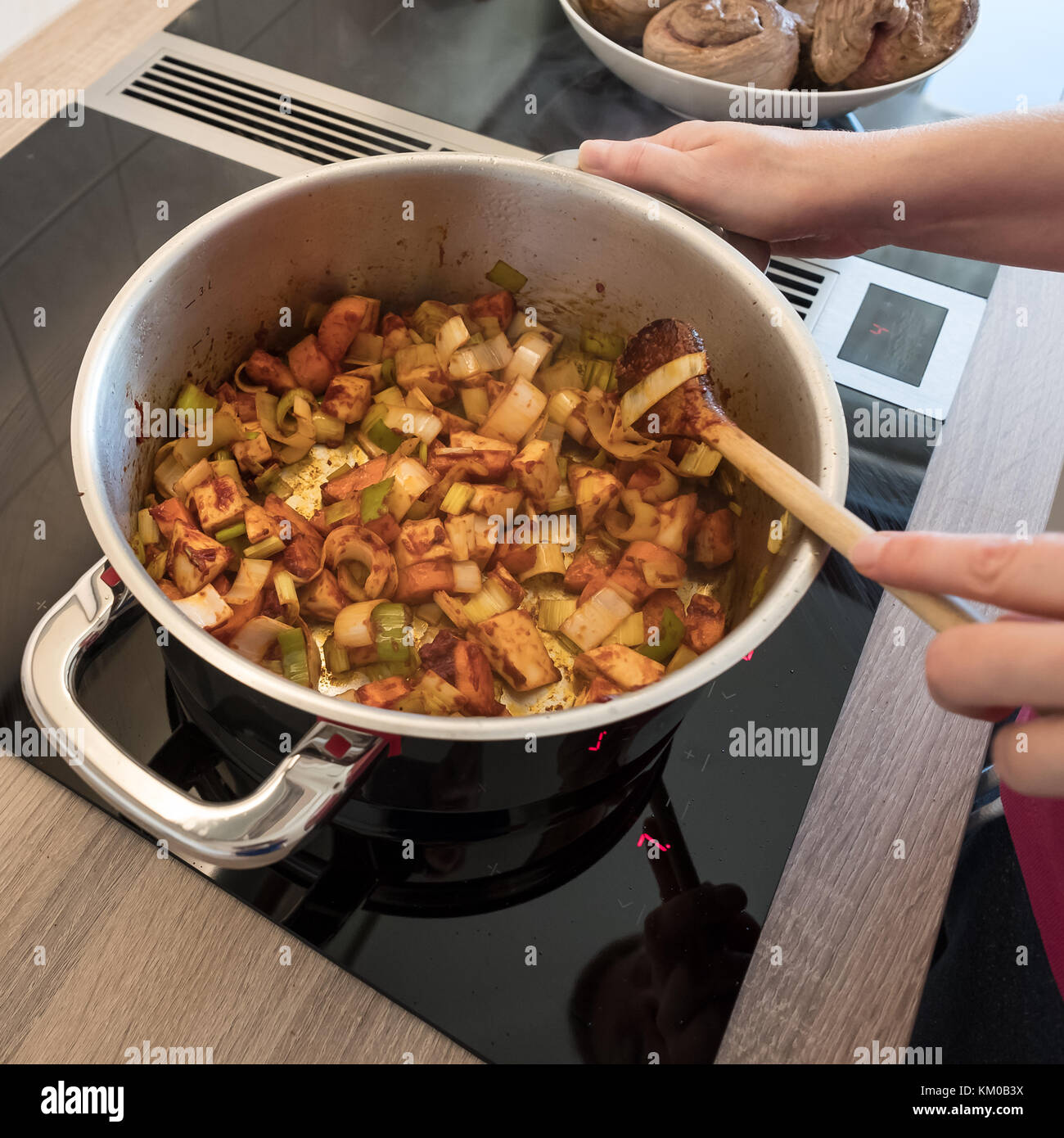 Weibliche hand dünsten Gemüse mit hölzernen Löffel in einem Kochtopf Stockfoto
