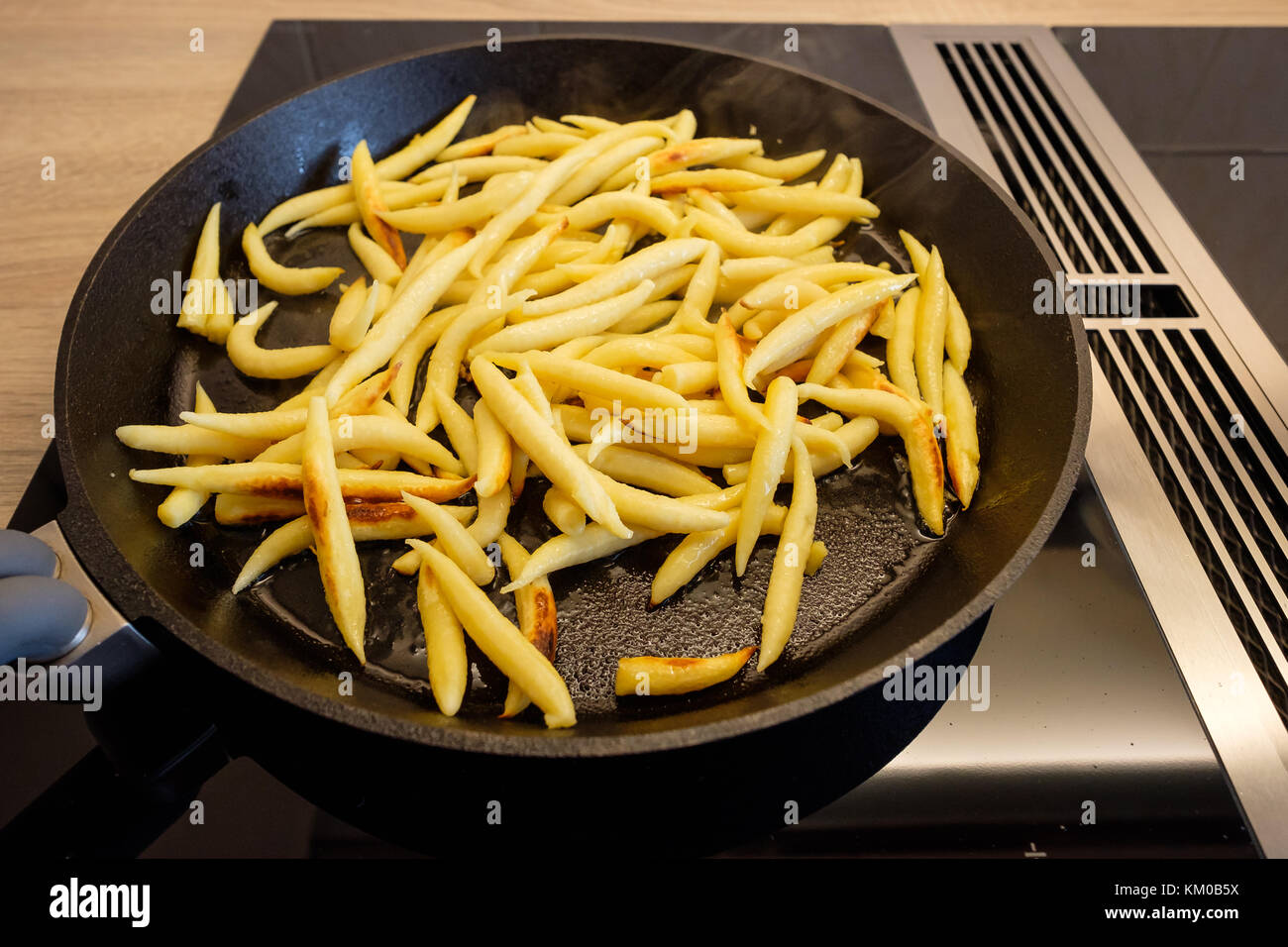 Kartoffelklöße braten in einer Pfanne Gusseisen auf einem Induktionsherd Stockfoto