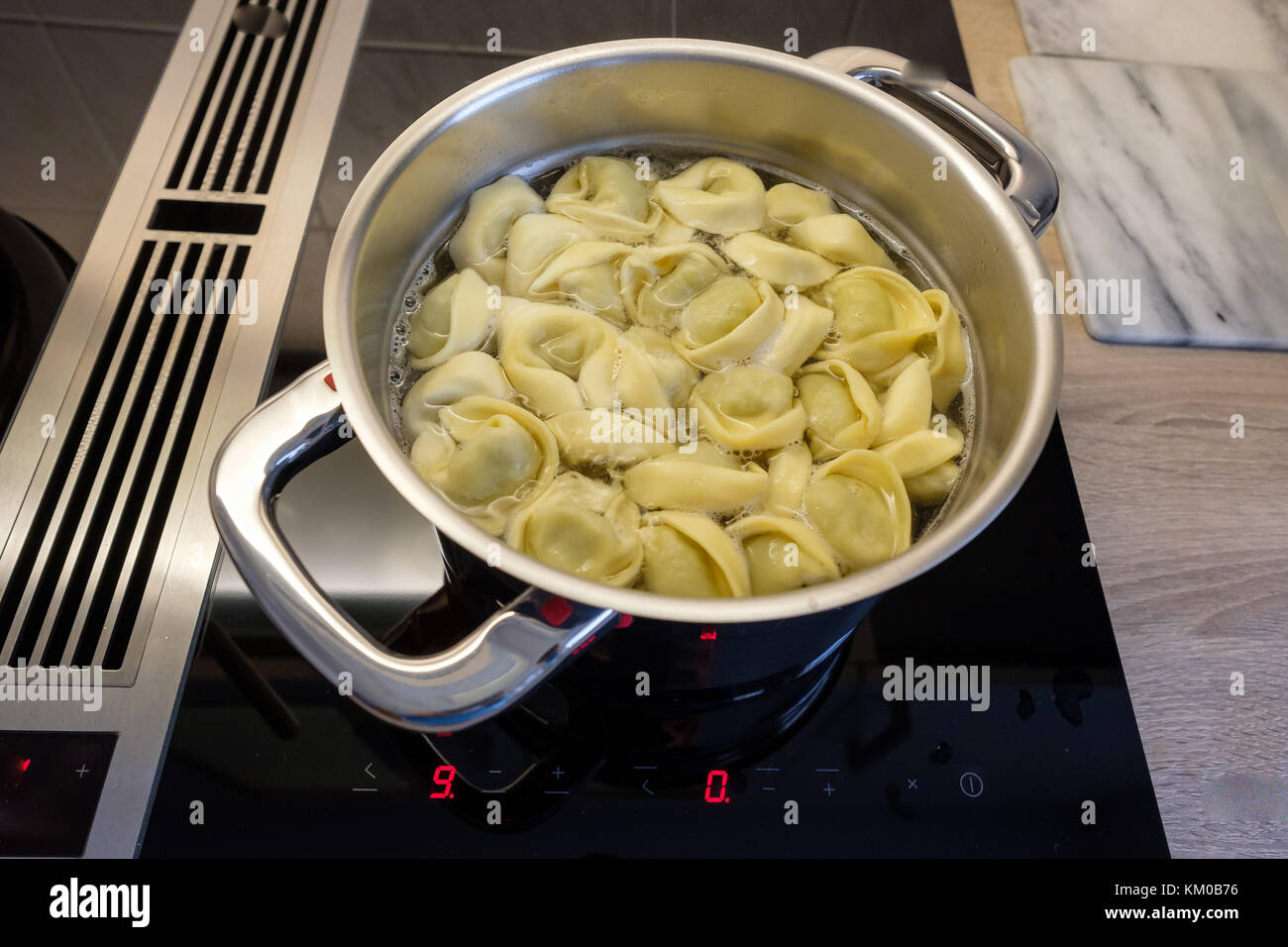 Kochtopf mit Tortellini Pasta auf einem Herd mit Dunstabzugshaube Stockfoto