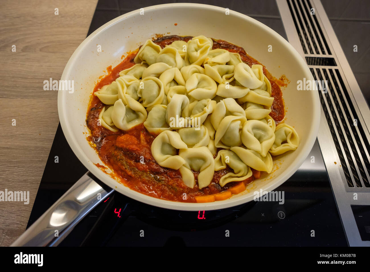 Pfanne mit Tortellini und Tomatensauce auf einem Kochfeld Stockfoto