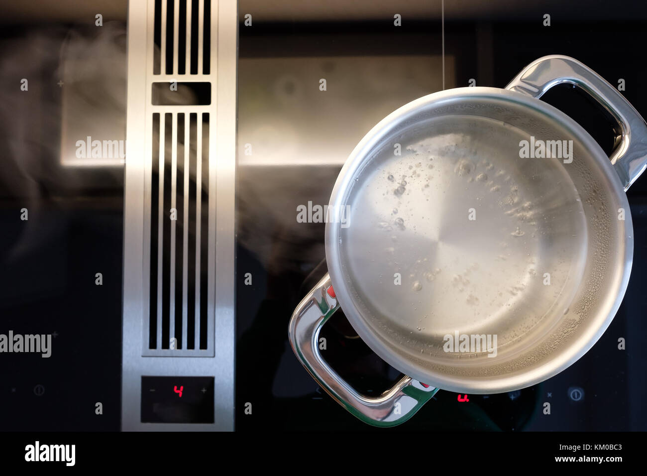 Kochendes Wasser in einem Kochtopf aus Edelstahl mit Dampf in die Dunstabzugshaube Stockfoto
