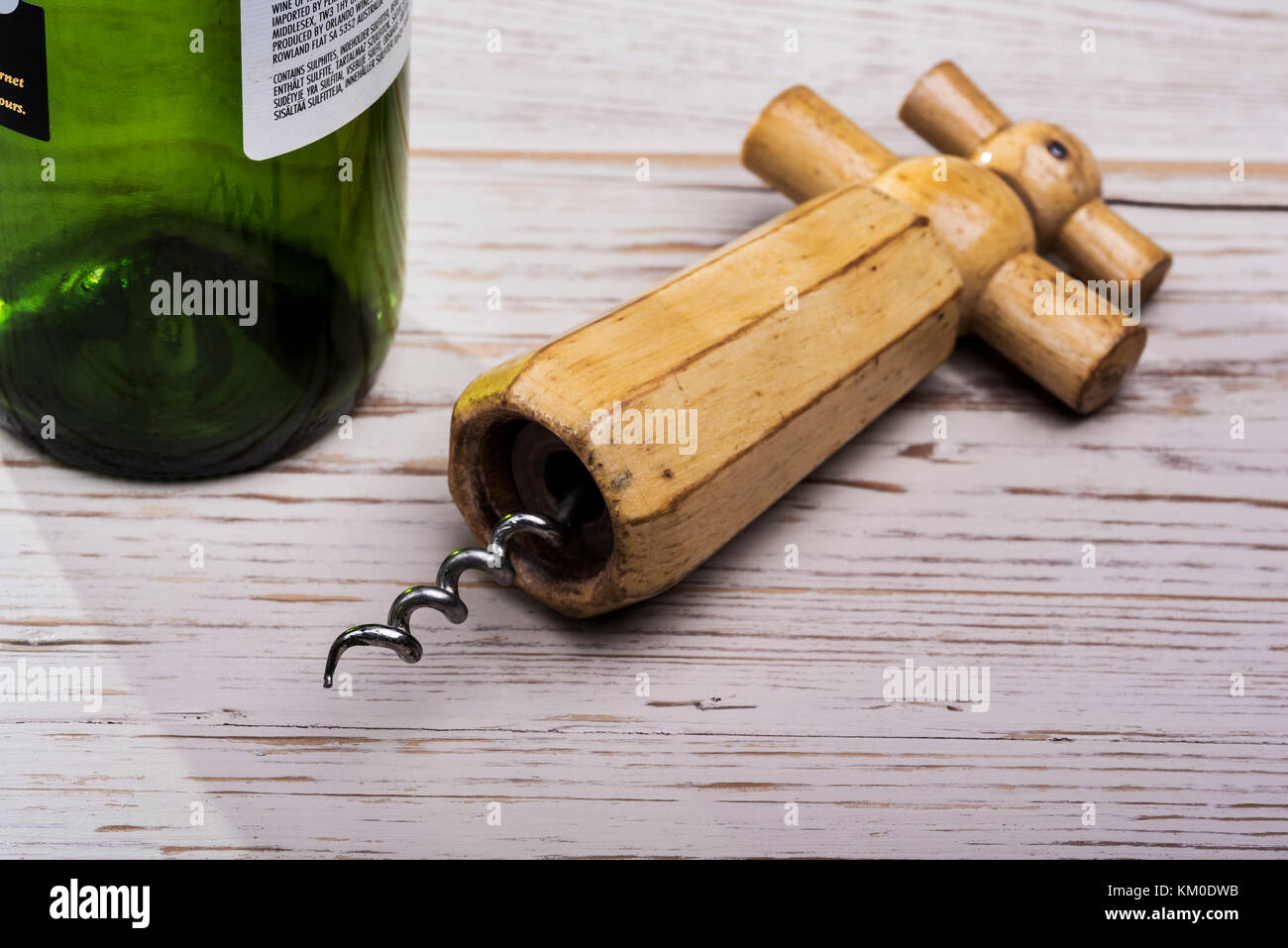 Alte, retro Holz Korkenzieher, auf distressed Holztisch mit leeren Flasche Wein. Stockfoto