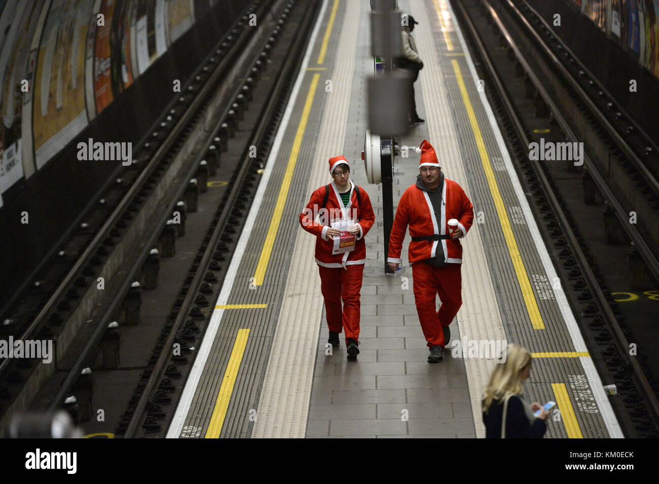 Verkleidet als Weihnachtsmann Spaziergang entlang einer U-Plattform, wie Leute trotzten dem Regen und Kälte während der Santa Dash in Clapham Common South West London, eine Spendenaktion Geld für Great Ormond Street Hospital (GOSH). Stockfoto