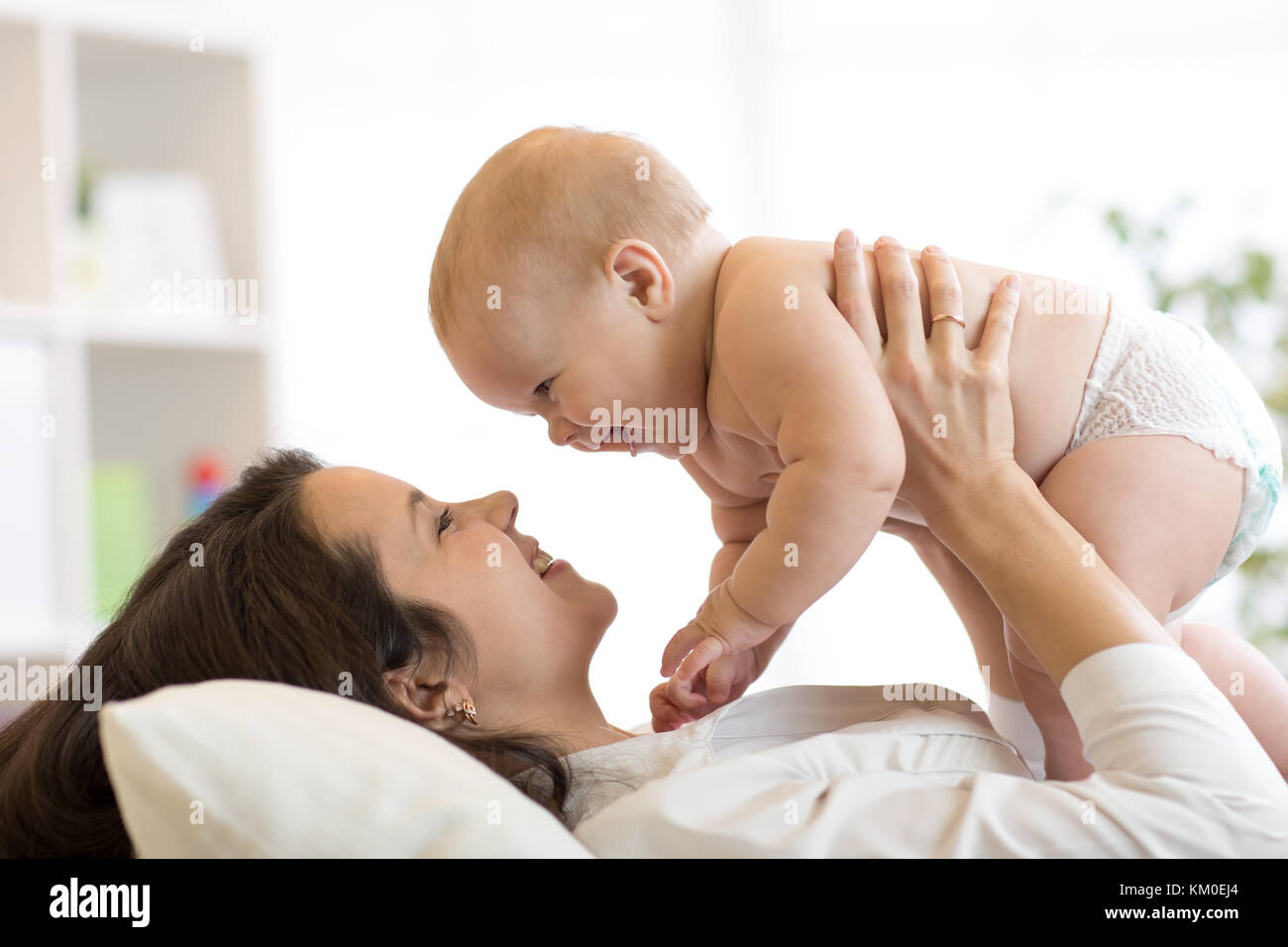 Mutter und Baby Schmusen und Spielen liegen im Innenbereich Stockfoto