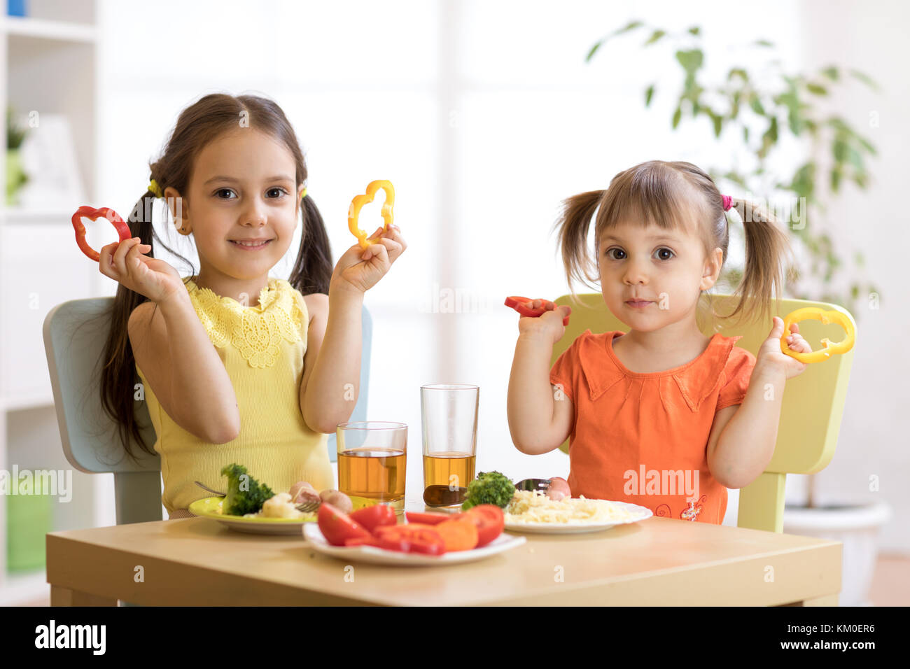 Lustige kleine Kinder spielen und essen im Kindergarten Stockfoto