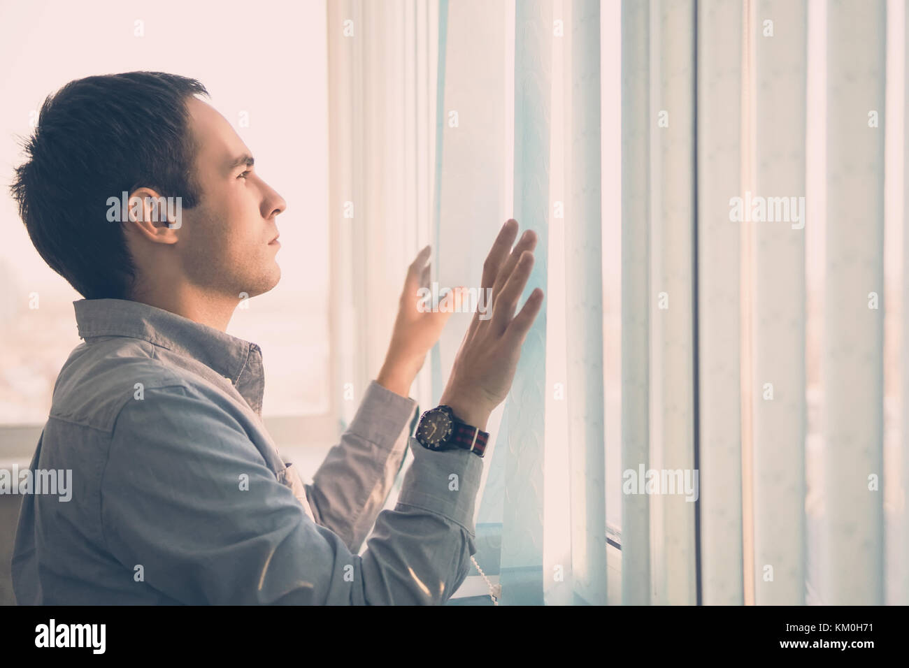 Junge Unternehmer stehen in modernen Büro, durch Blinde suchen, denken. vertikale Jalousien Licht blaue Farbe auf dem großen Bildschirm. Stockfoto