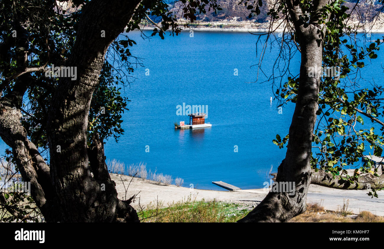Kleine Schwimmdocks und Kabine in der Kalifornischen Lake Cachuma durch zwei Baumstämme gerahmt Stockfoto