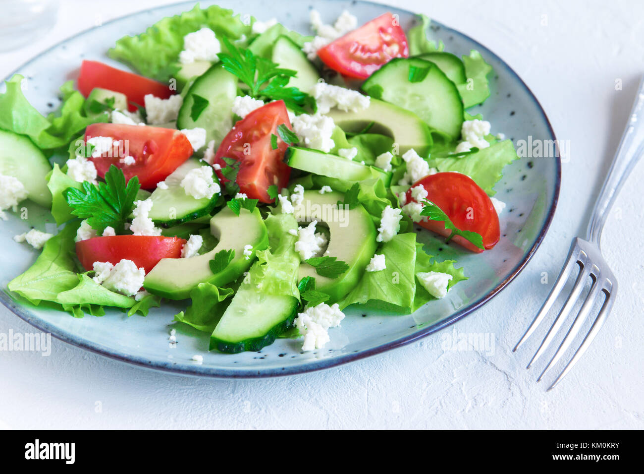 Grüner Salat mit Avocado in Scheiben, Tomaten, Gurken und griechischer ... Grüner Salat mit Avocado in Scheiben, Tomaten, Gurken und griechischer ...