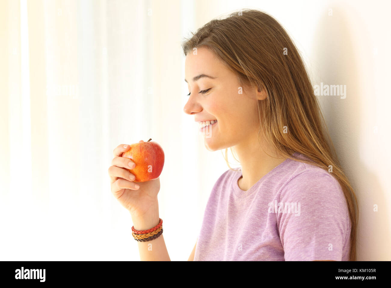 Seitenansicht Portrait Of Happy Teen bereit, einen Apfel zu essen drinnen Stockfoto