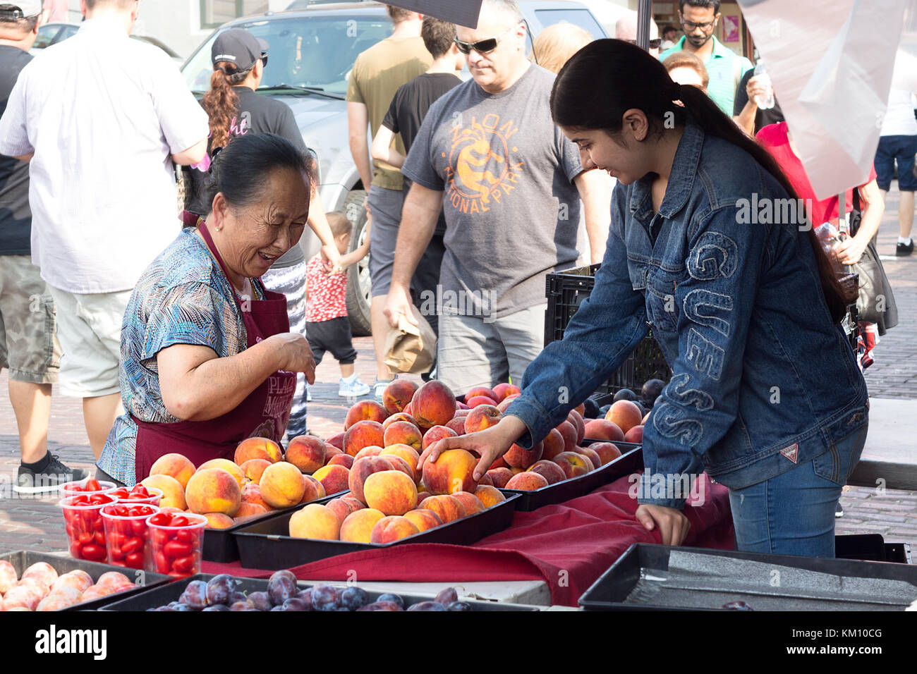 Seattle, Washington, USA - 4. September 2017: eine asiatische Frau sind Auswahl und Verkauf Pfirsiche an Farmers Market in Pike Market in Seattle Hafen, Waschen Stockfoto