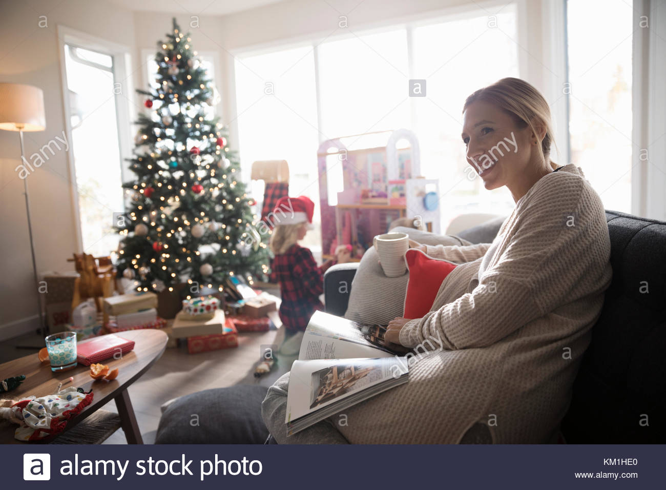 Lächelnde Frau entspannende, Kaffee trinken und lesen Magazin in Weihnachten Wohnzimmer Stockfoto
