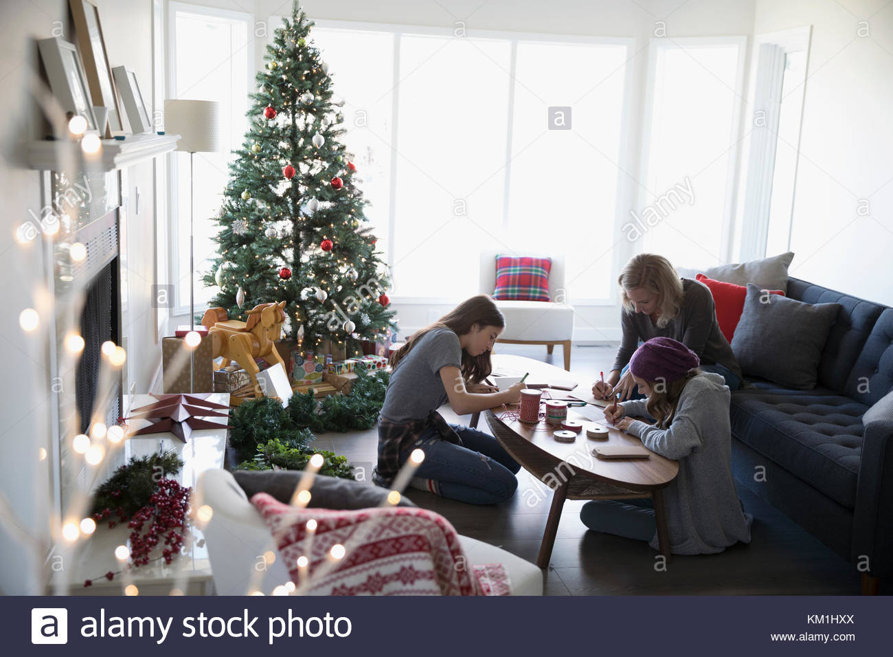 Mutter und Töchter zu Weihnachten Karten in der Nähe von Weihnachten Baum im Wohnzimmer Stockfoto