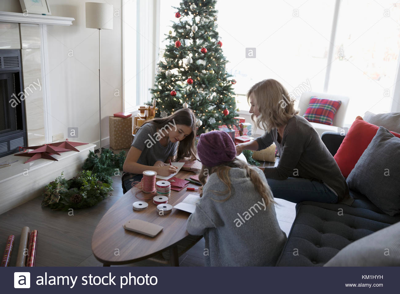 Mutter und Töchter zu Weihnachten Karten in der Nähe von Weihnachten Baum im Wohnzimmer Stockfoto