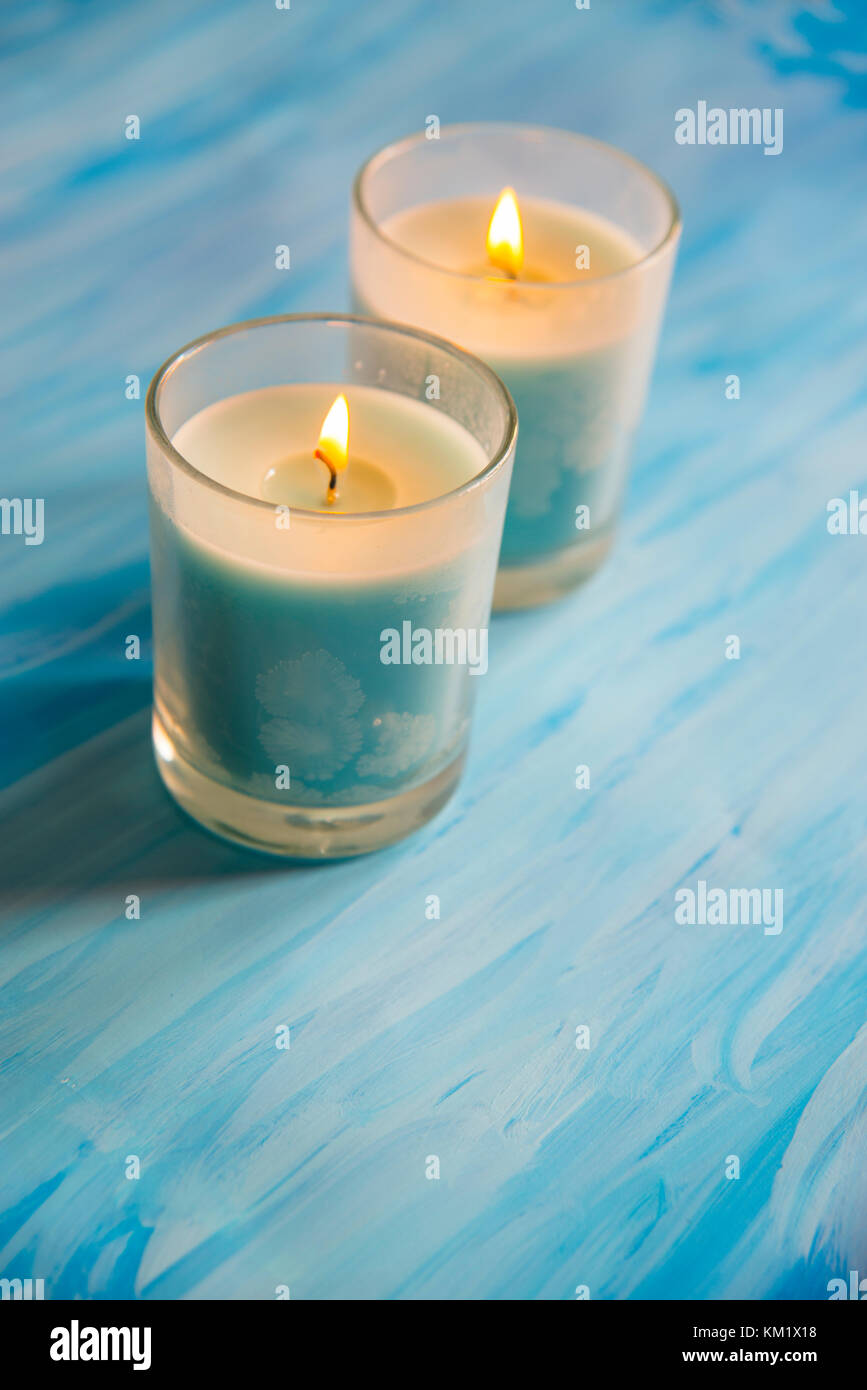 Zwei leuchten Kerzen auf blauen Fläche. Stockfoto