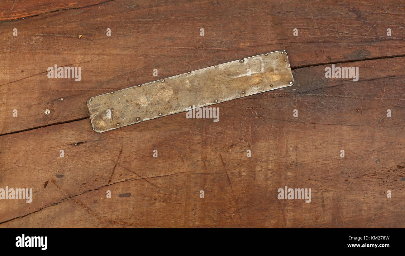 Grunge Hintergrund Textur von braunem Holz mit schmutzigen Flecken, Kratzer, Risse und genagelt Zinnmetall Patch, in der Nähe Stockfoto