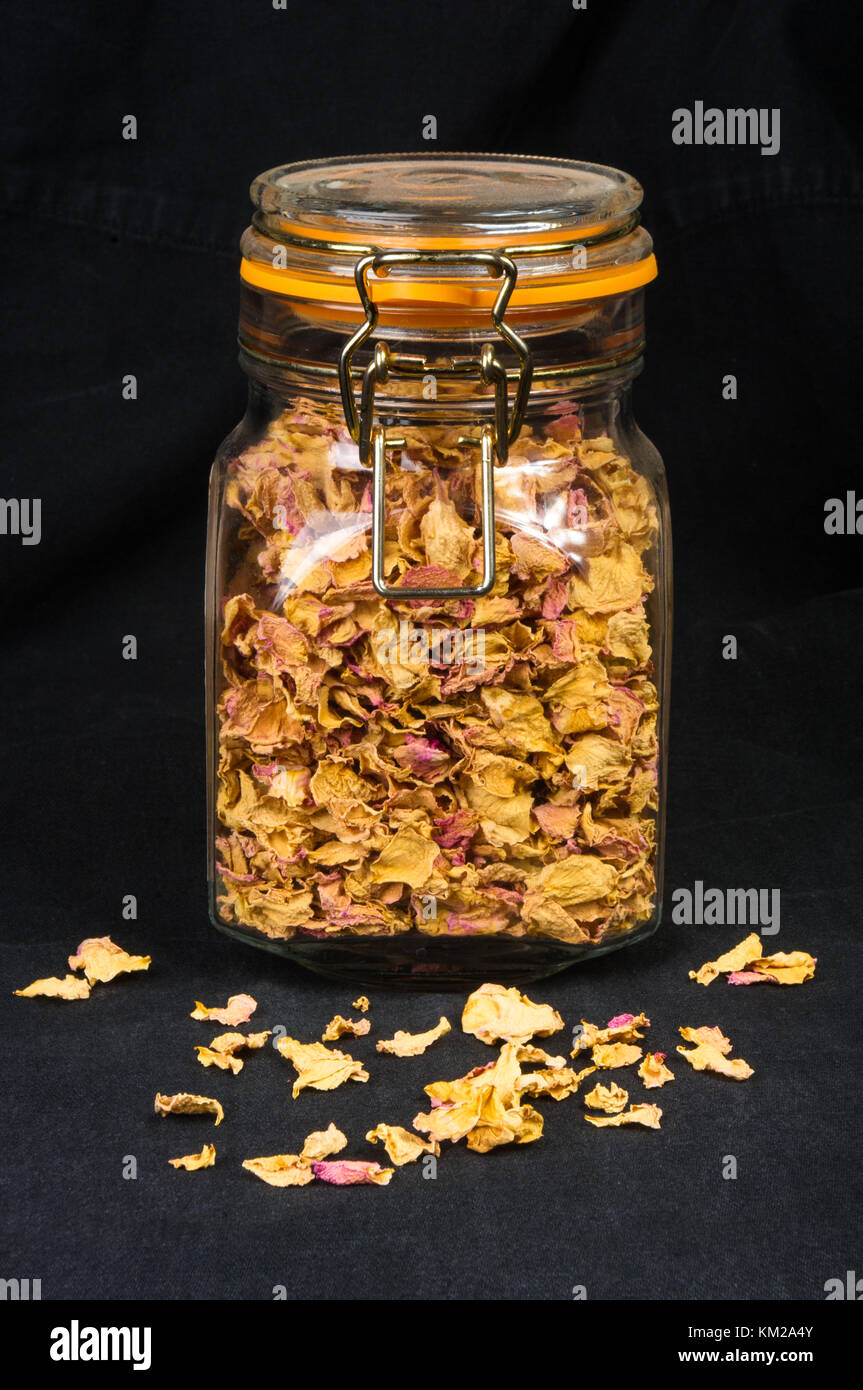 Rose getrocknete Blütenblätter in einem Glas mit Deckel auf schwarzem Hintergrund Stockfoto