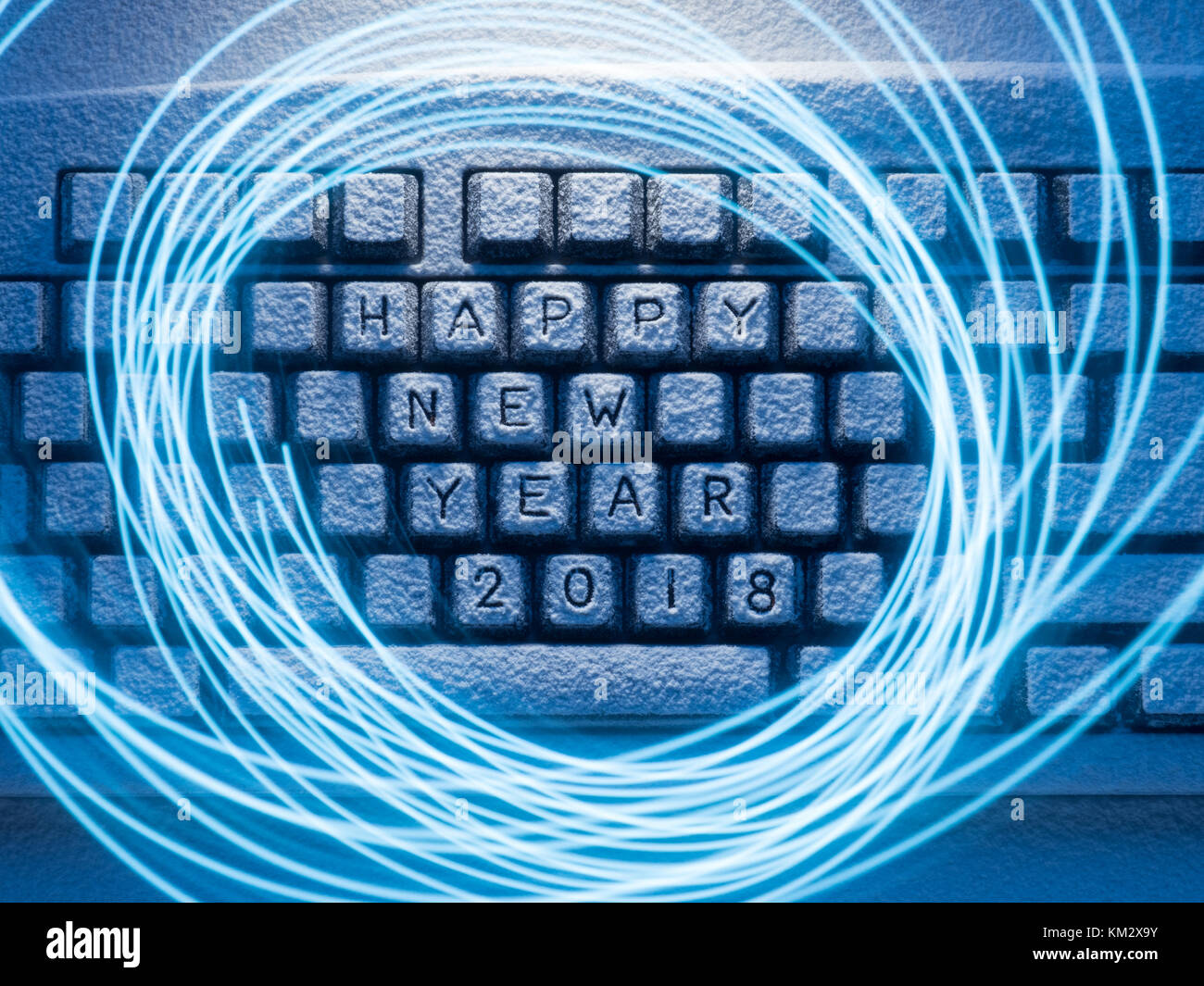 Computer Tastatur mit Schnee durch blaues Licht leuchtet auf, wenn die Kreise, die durch blaues Licht malte auf einer langen Belichtungszeit mit der Aufschrift Neuen ja glücklich abgedeckt Stockfoto