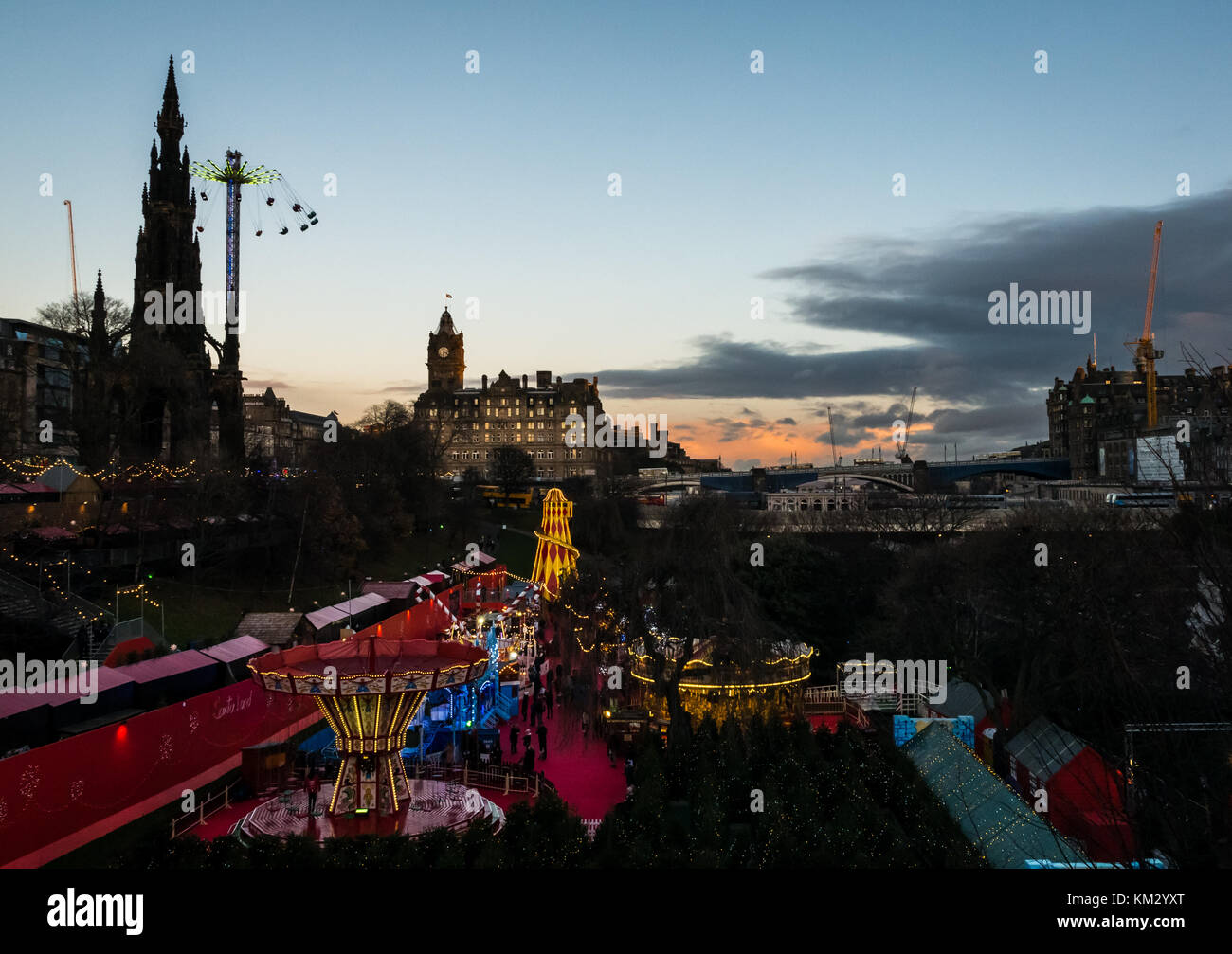 Weihnachtsmarkt, Princes Street Gardens, Edinburgh, Schottland, Großbritannien, in der Dämmerung mit Scott Monument, Star Flyer und Balmoral Hotel Clock Tower leuchtet Stockfoto