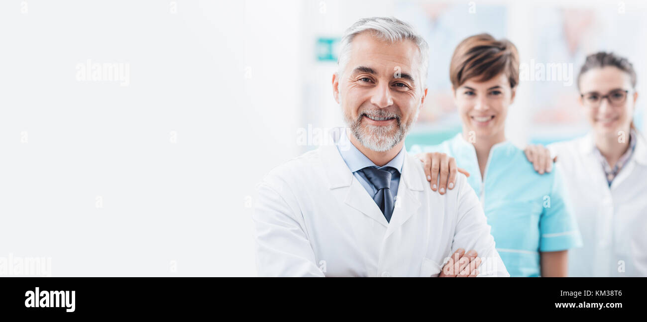 Ärzte und medizinisches Personal posiert im Krankenhaus und halten einander die Schultern, Teamarbeit und healthcare Banner Stockfoto
