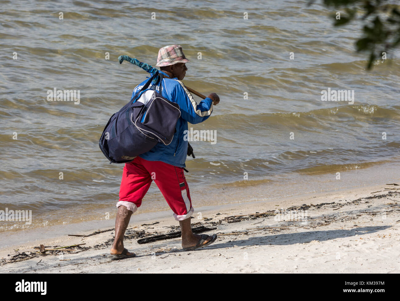 Ein madagassischer Mann, der einen Seesack Spaziergänge am Ufer des Sees ampitabe. Madagaskar, Afrika. Stockfoto
