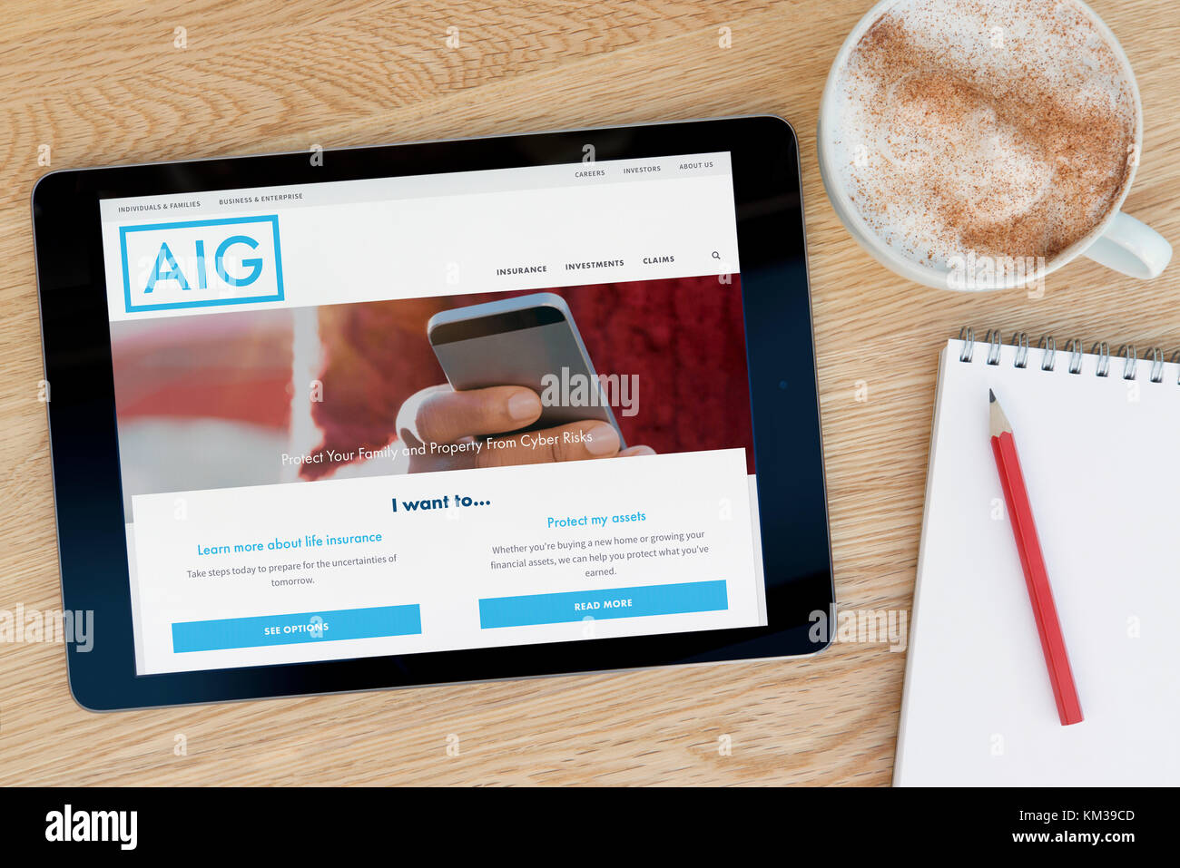 Die AIG insurance Website auf einem iPad Tablet Gerät, das auf einem Tisch liegt neben einem Notizblock und Bleistift und eine Tasse Kaffee (nur redaktionell) Stockfoto