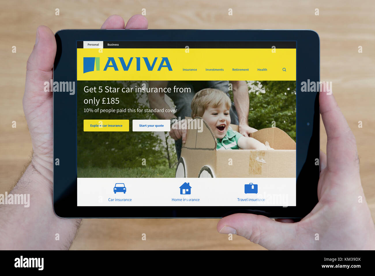 Ein Mann sieht im Aviva Website auf seinem iPad tablet device, Schuß gegen einen hölzernen Tisch top Hintergrund (nur redaktionelle Nutzung) Stockfoto
