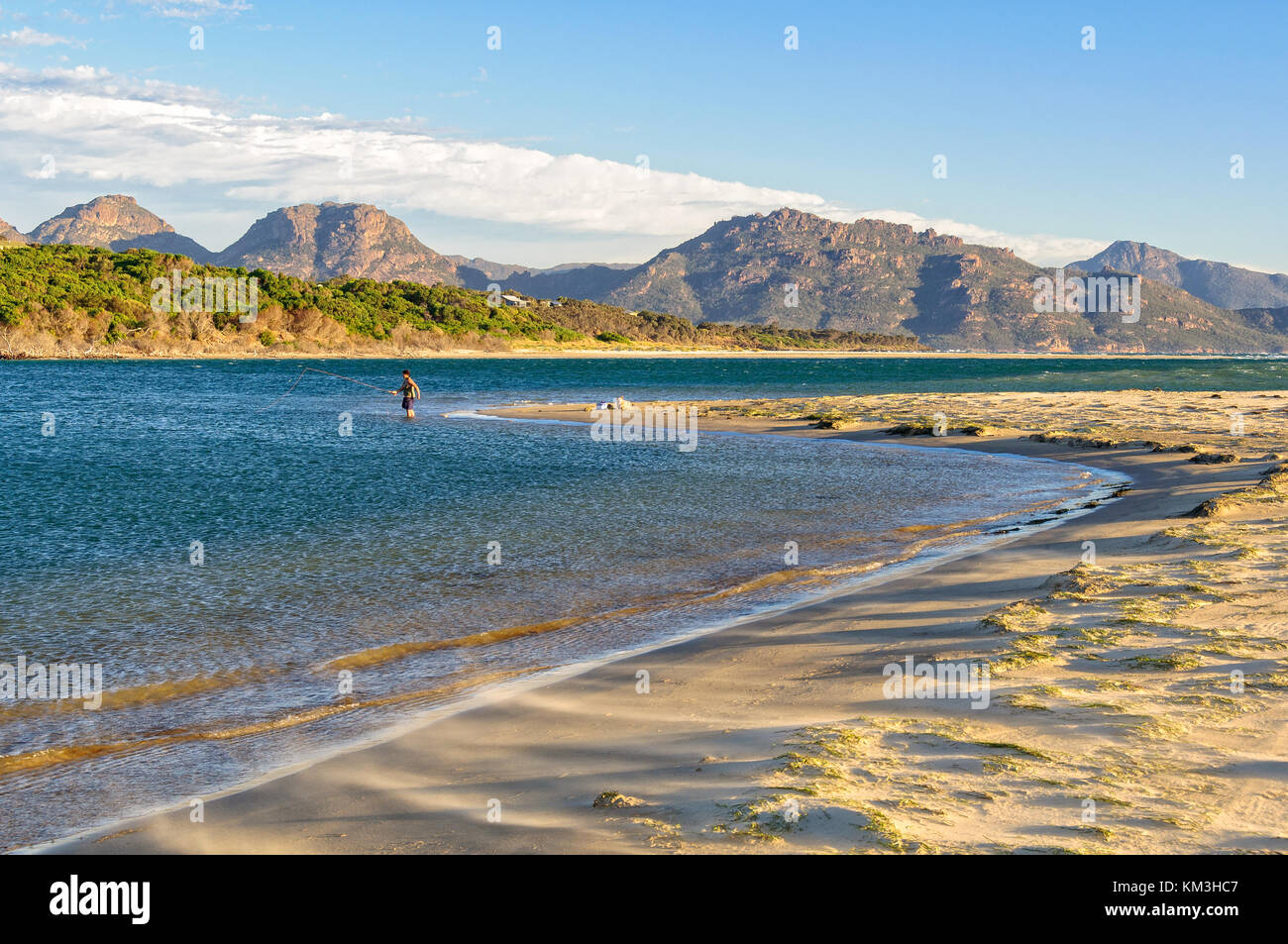 Ein angler im flachen Wasser auf der 9 Mile Beach in der Nähe von Swansea mit den Freycinet National Park in der Ferne - Tasmanien, Australien Stockfoto